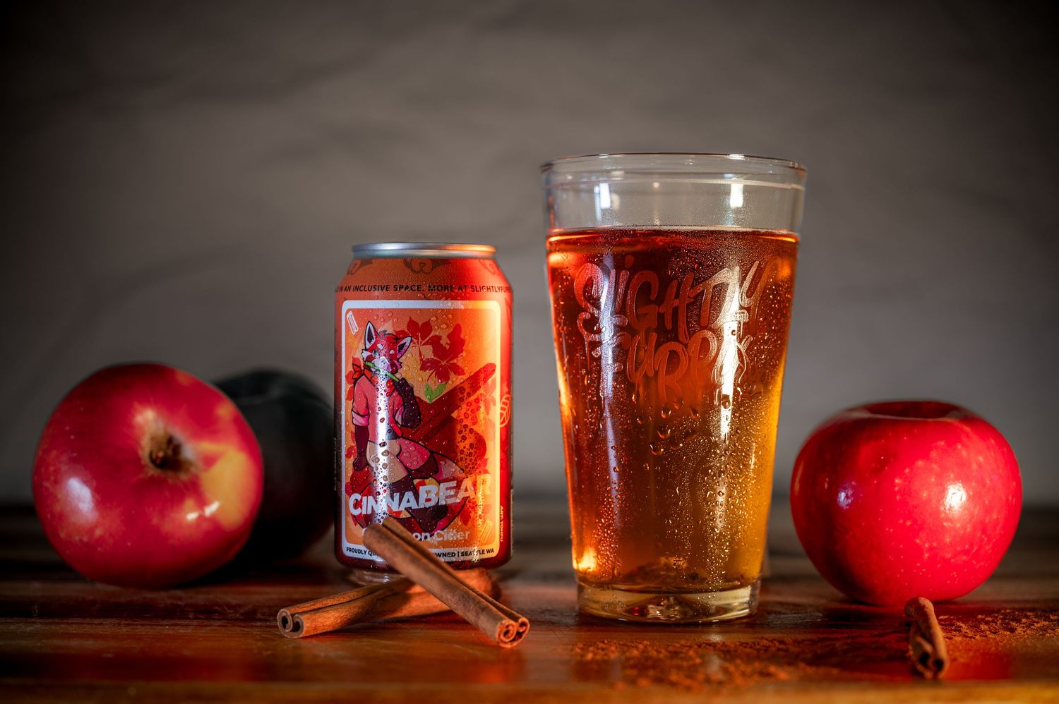 Still life composition of red apples and glasses of amber beer on a rustic wooden surface.