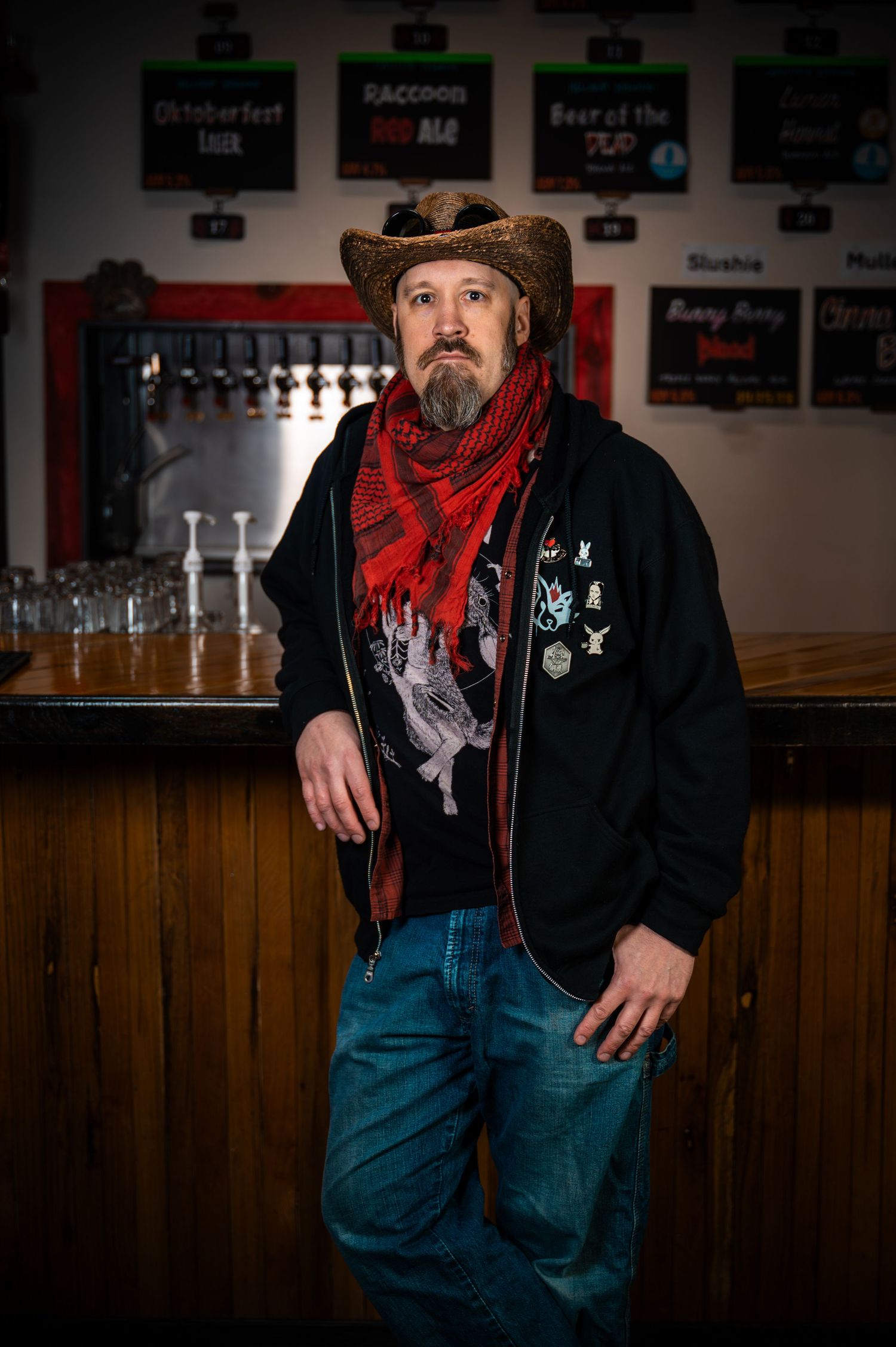 Person in casual attire with red bandana standing against wooden paneled wall in dim lighting.