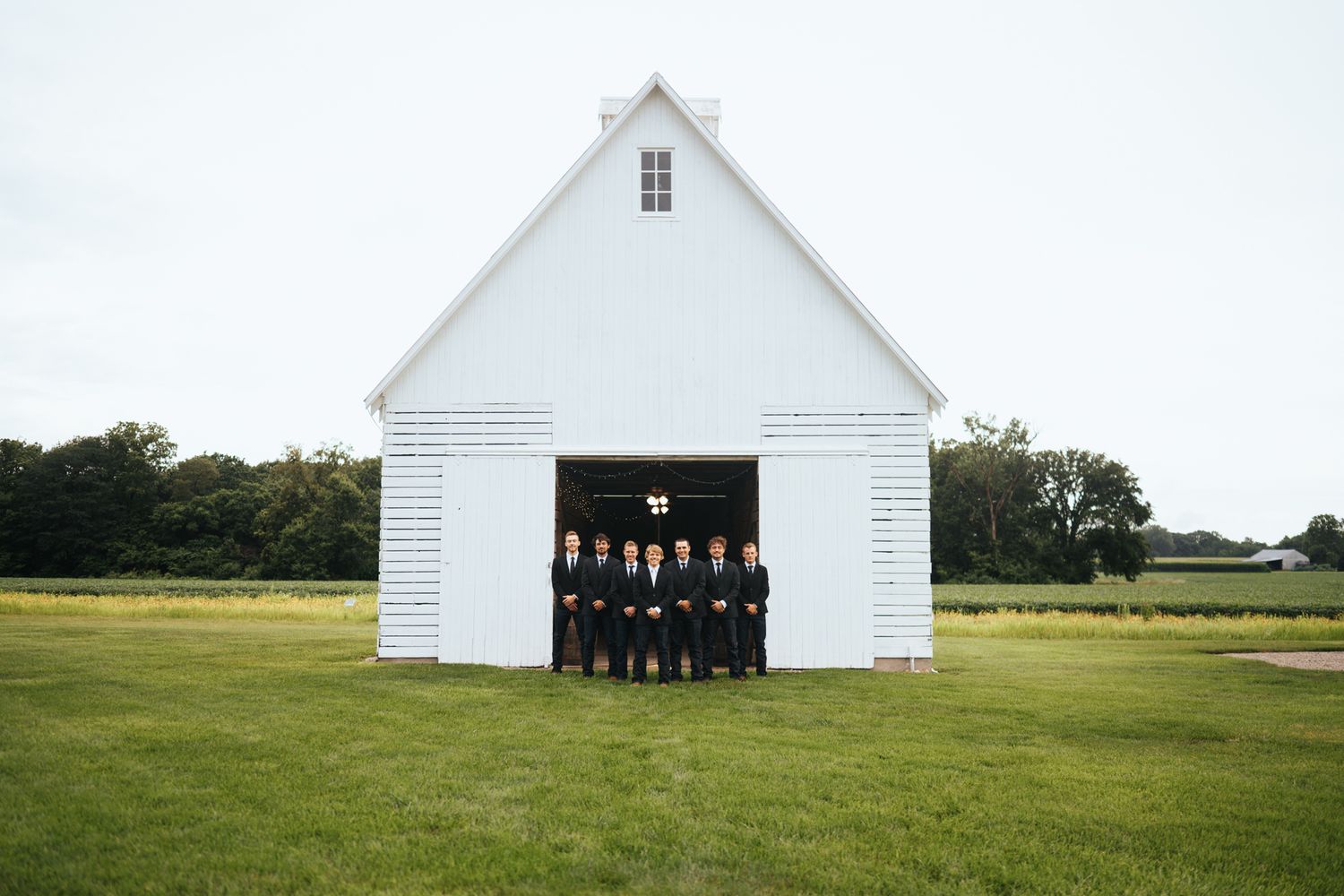 A panoramic view of a classic white barn in a green countryside setting.