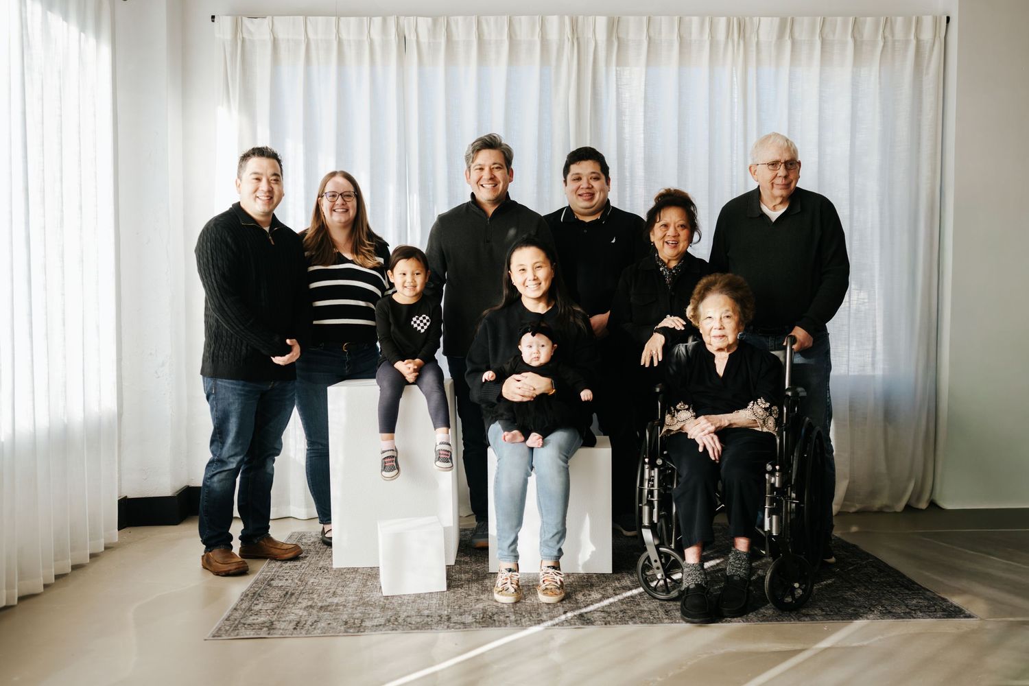 A group photo series showing people posing together in a bright white studio space with curtains and a rug.