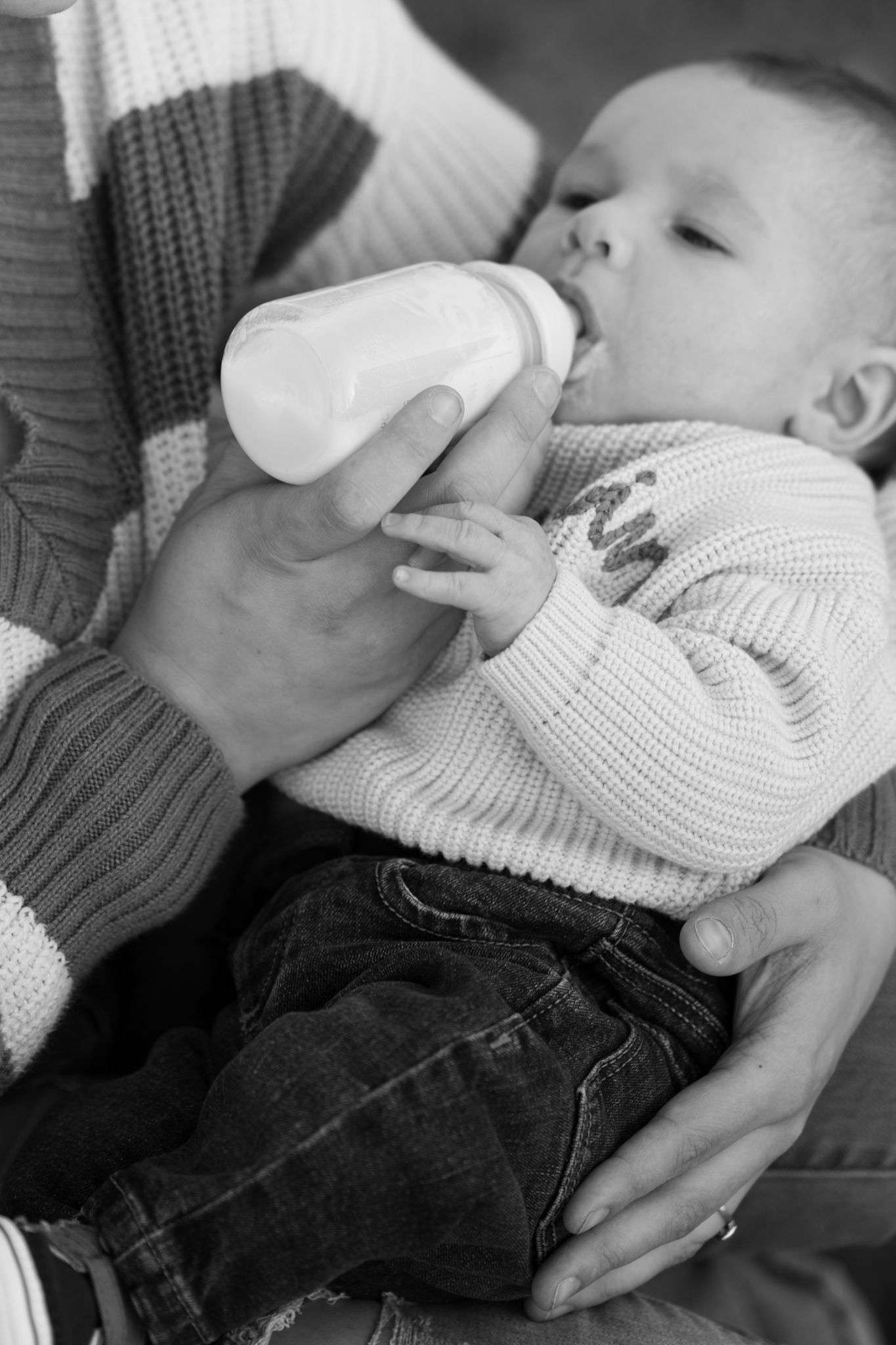 Black and white close-up images showing hands gently touching a knitted sweater and denim fabric.