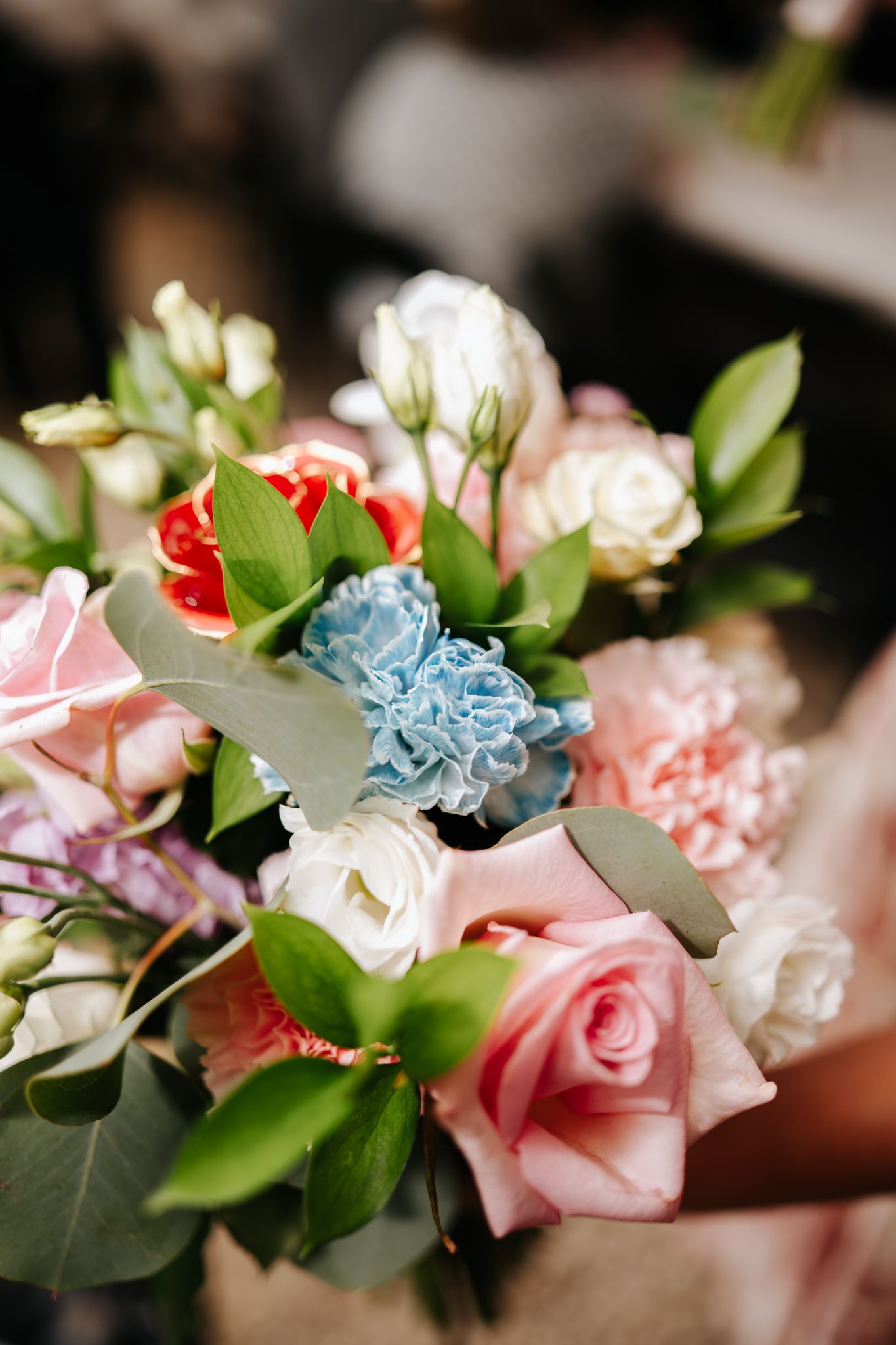 Delicate floral arrangement featuring pink, blue and white flowers with green foliage.