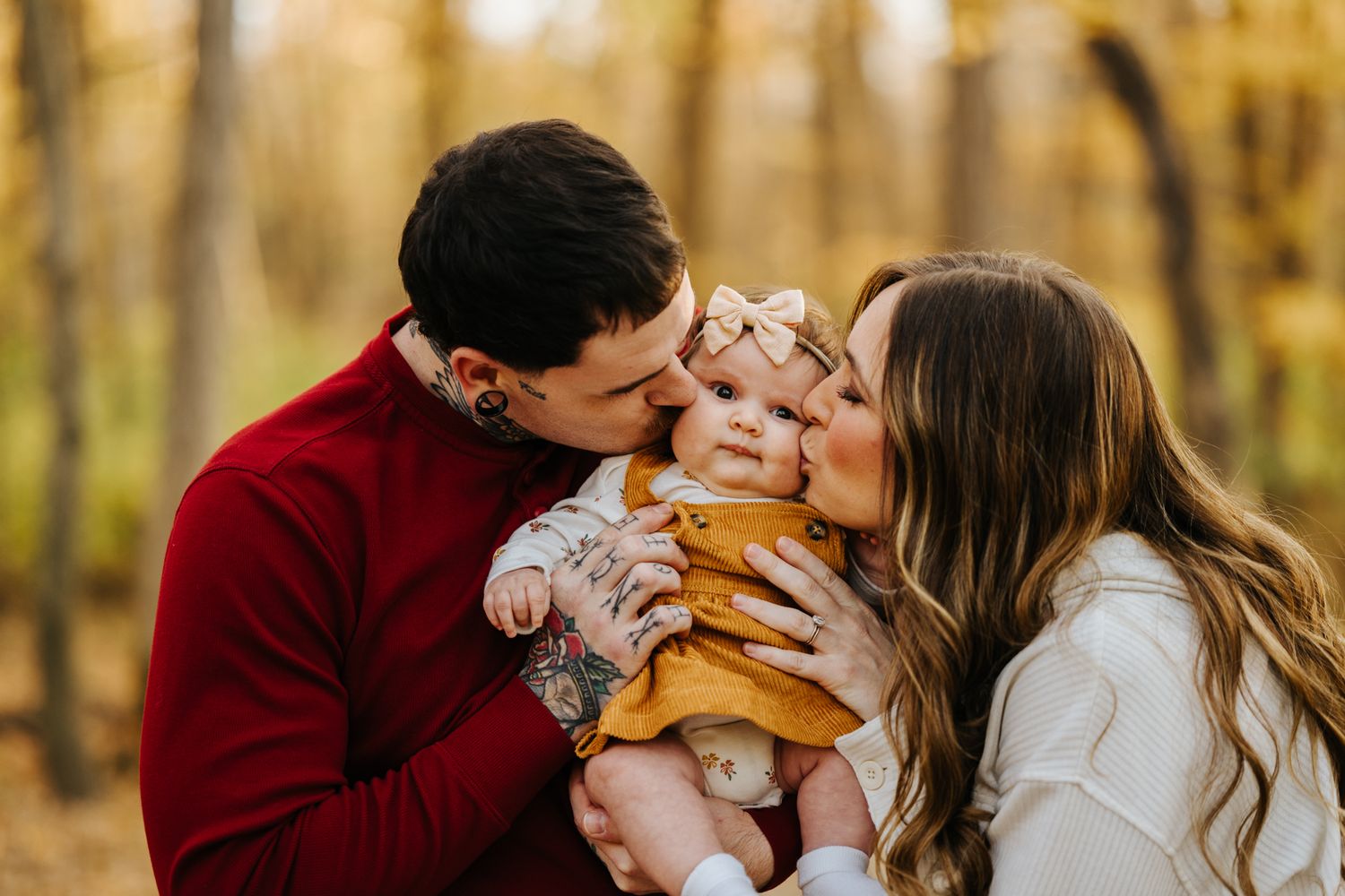 Family sharing tender moments together in golden autumn forest setting.