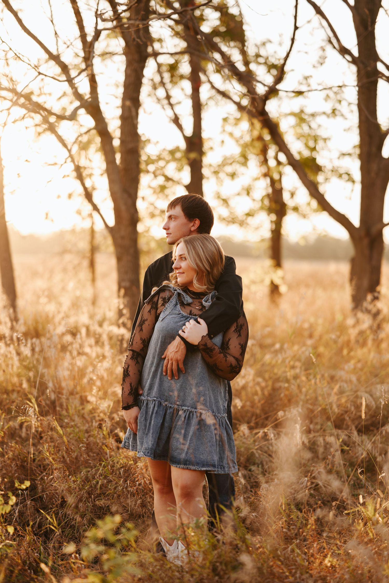 Two people share tender moments in a golden sunset among trees.