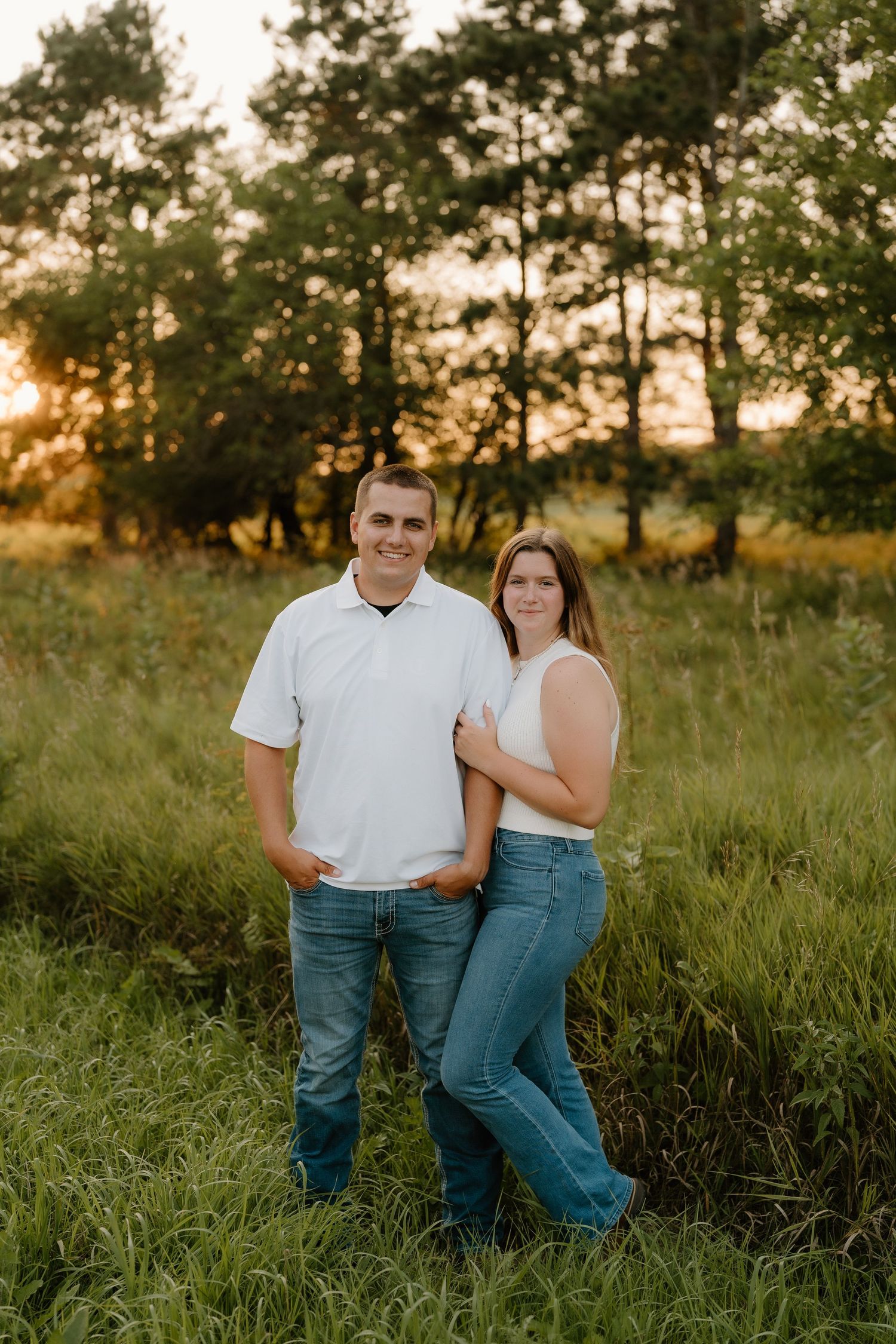 Casual couple's portrait session in a grassy field at sunset.