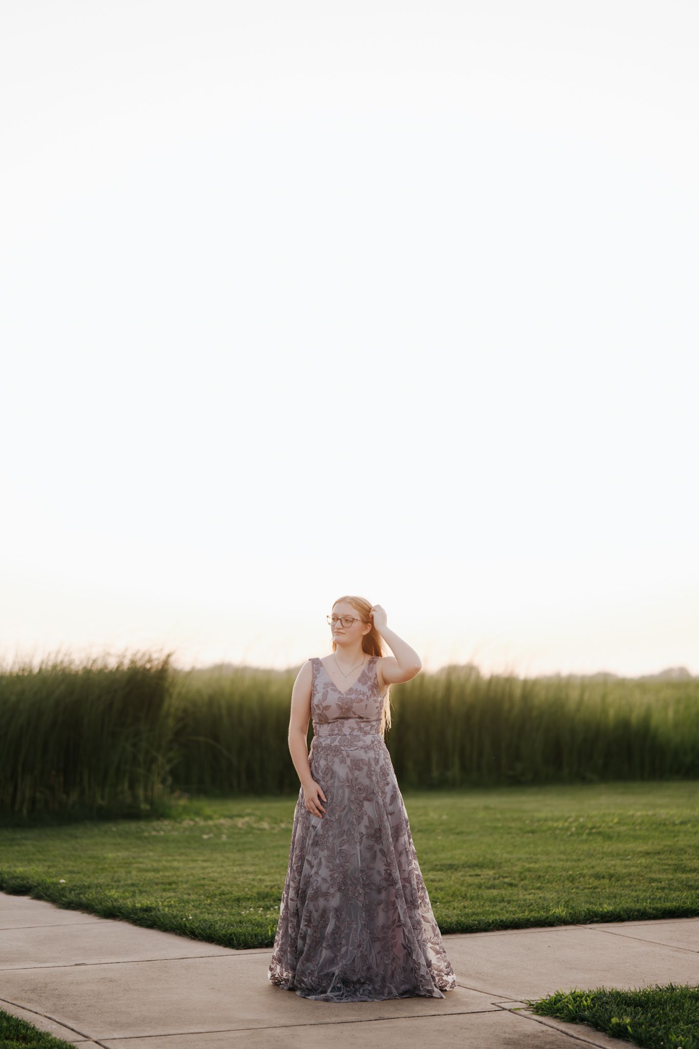 Person in purple dress posing in an open field during sunset.