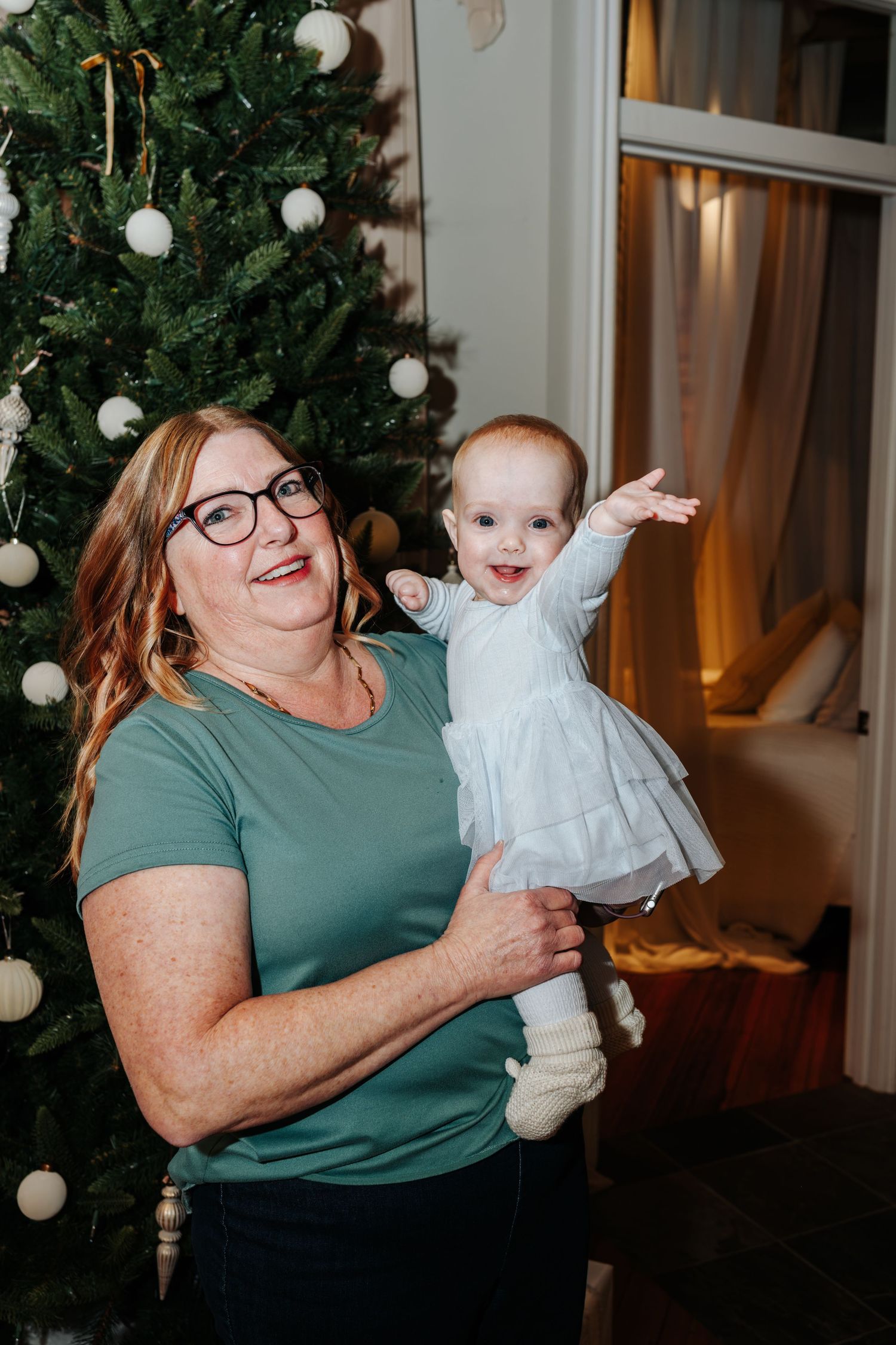 Four sequential photos showing joyful holiday moments between an adult and baby in front of a Christmas tree.