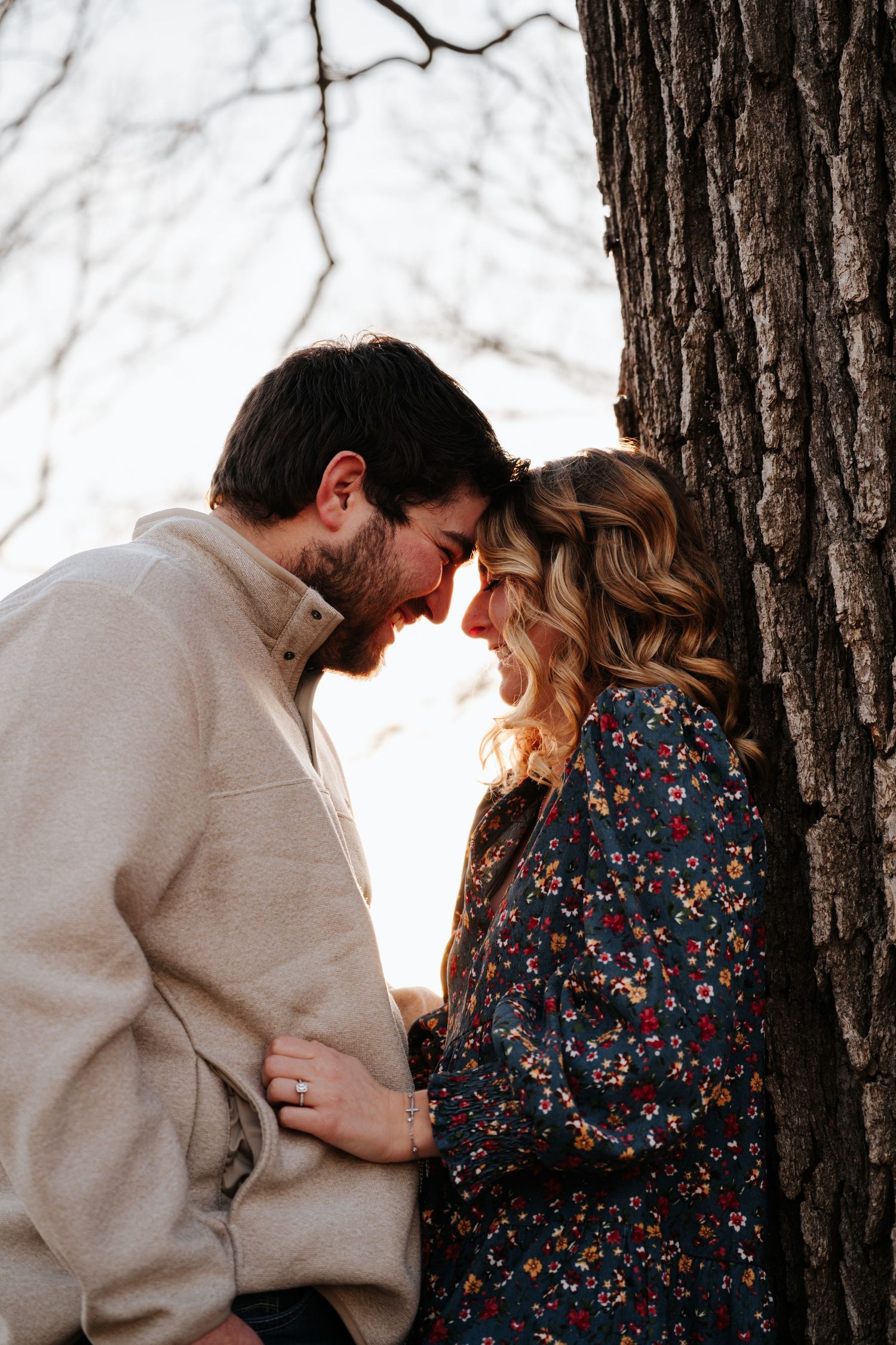 A romantic couple shares intimate moments in a forest setting wearing neutral and floral clothing.