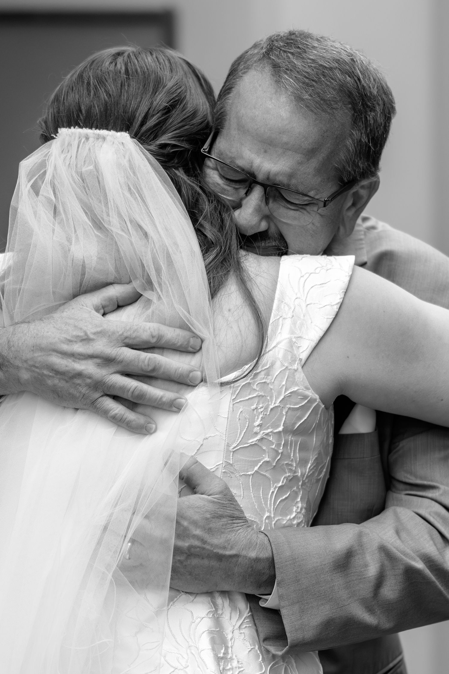 Black and white photo showing emotional embraces during wedding moments.