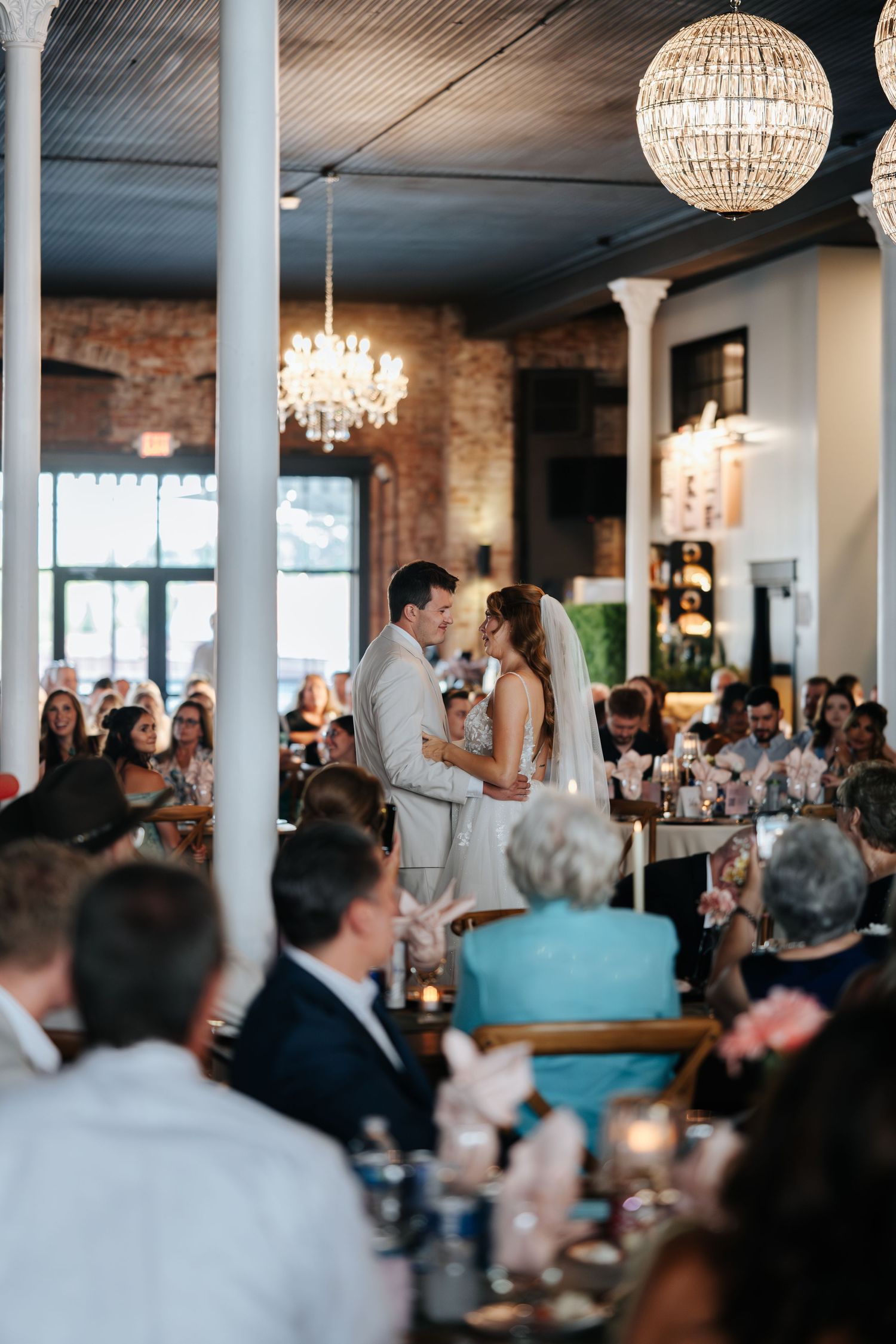 Wedding reception venue with crystal chandeliers and exposed brick walls.