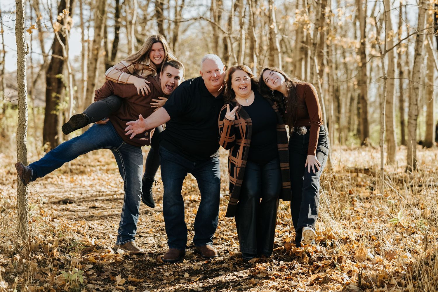 A group sits together on fallen logs in an autumn forest during a casual outdoor photoshoot.