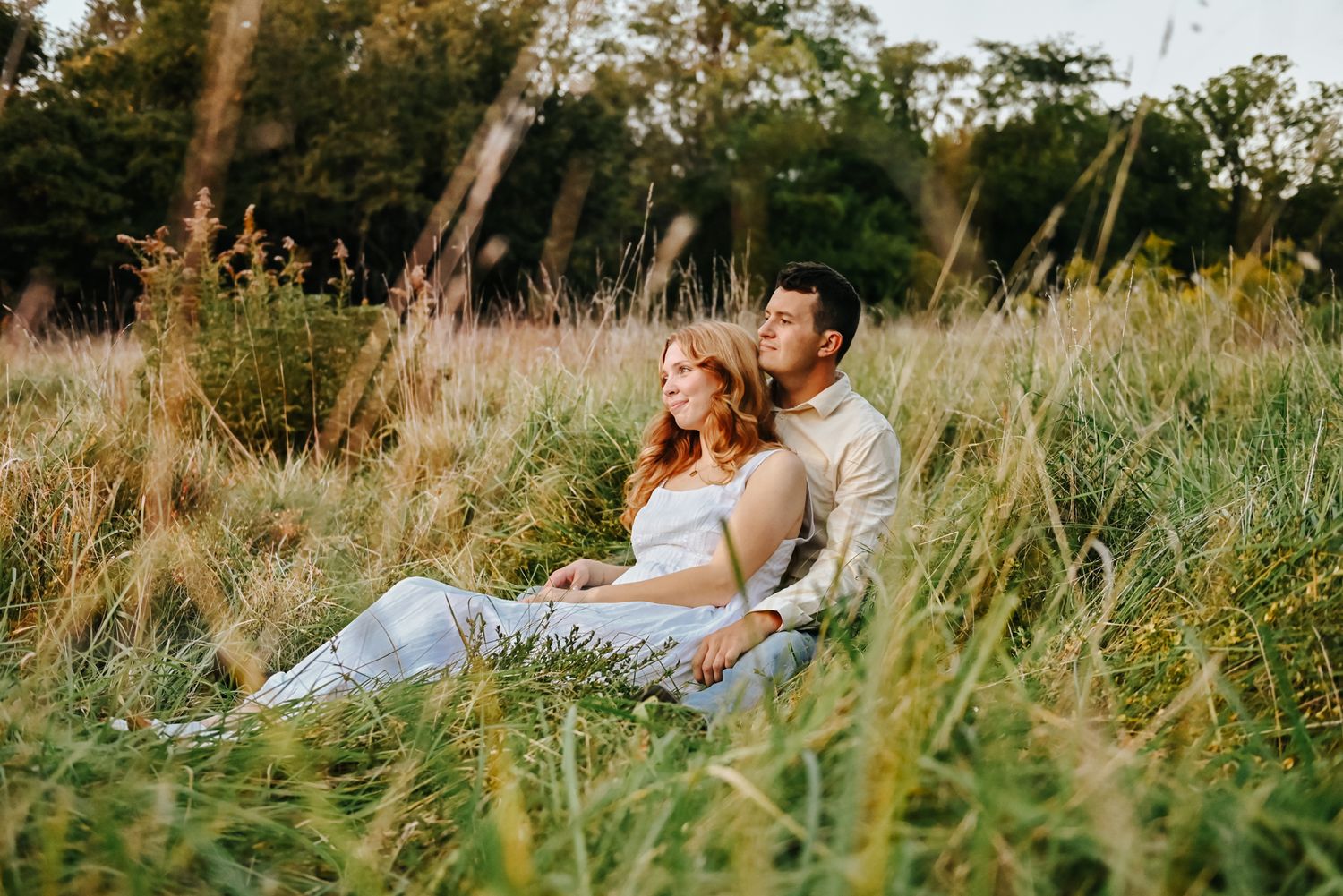 Romantic couple lounging in tall grass during golden hour.