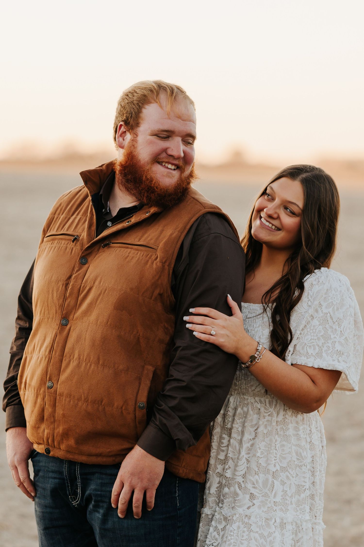 A couple shares intimate moments during a sunset photoshoot in a field.