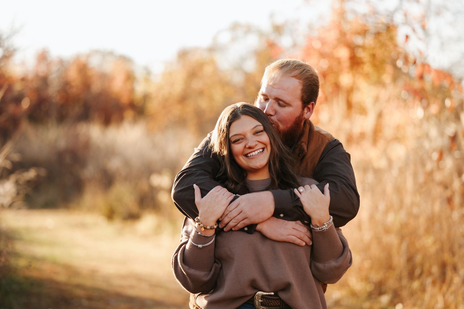 A family shares tender moments together during a golden hour photo session in a field.
