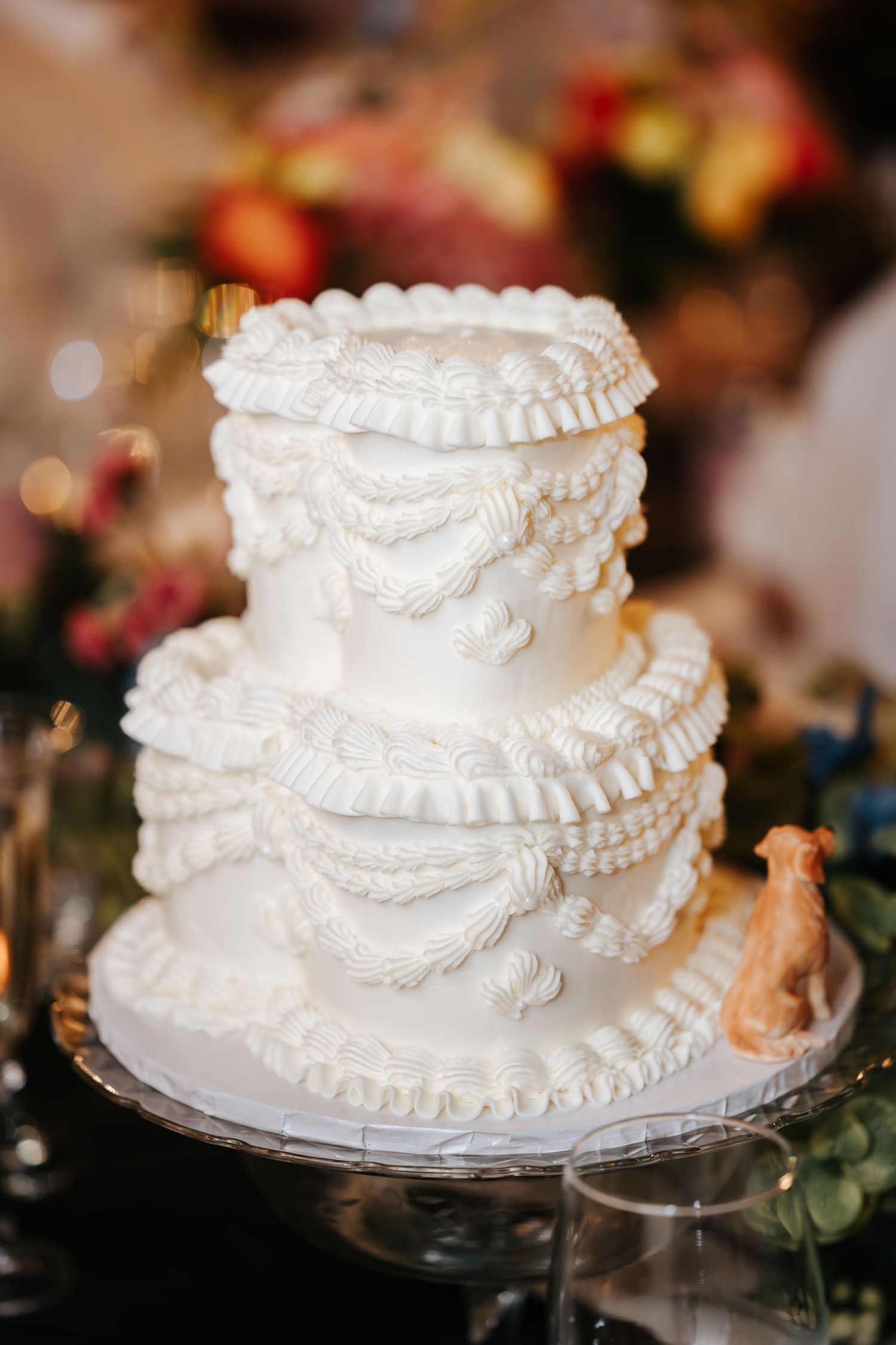 Elegant white wedding cake with intricate ruffle details on display.