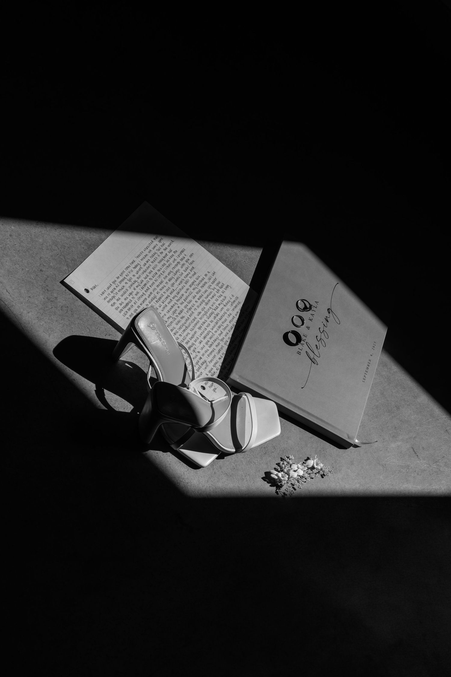 Black and white artistic shot of wedding vows and rings in dramatic lighting.