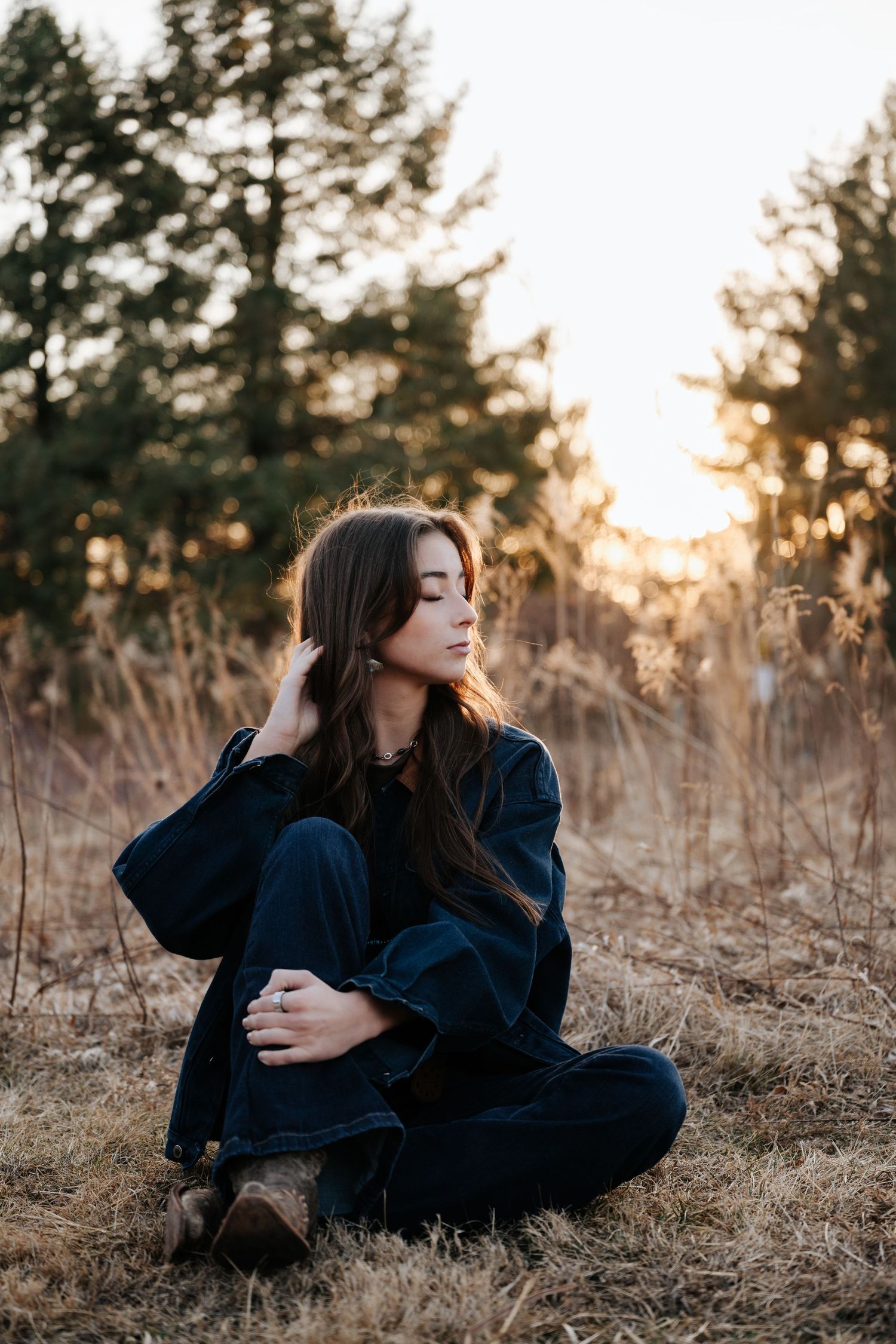 Person in dark clothing reclining in golden sunlit field at sunset.