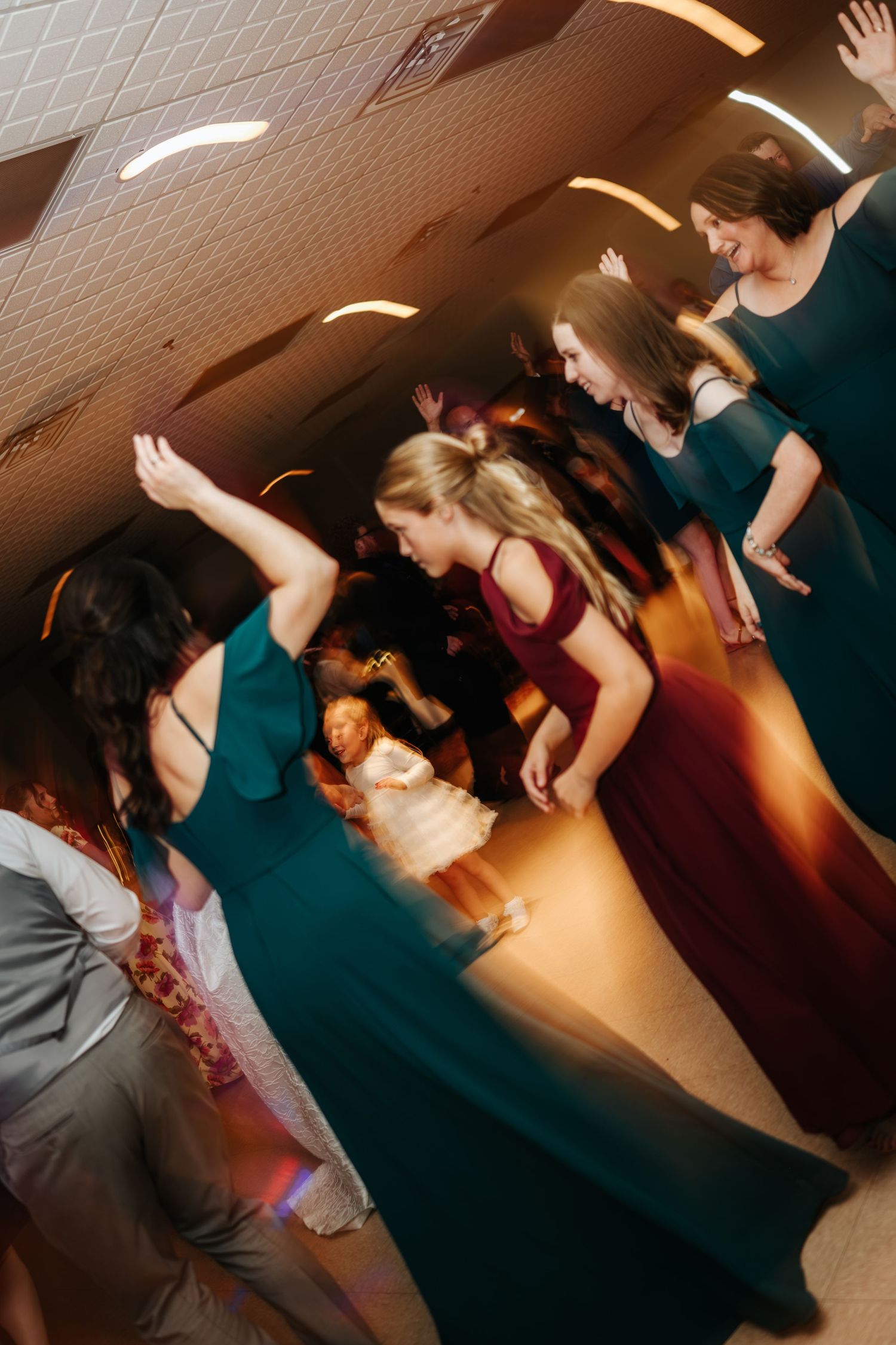 Wedding guests dancing energetically on a dimly lit dance floor.