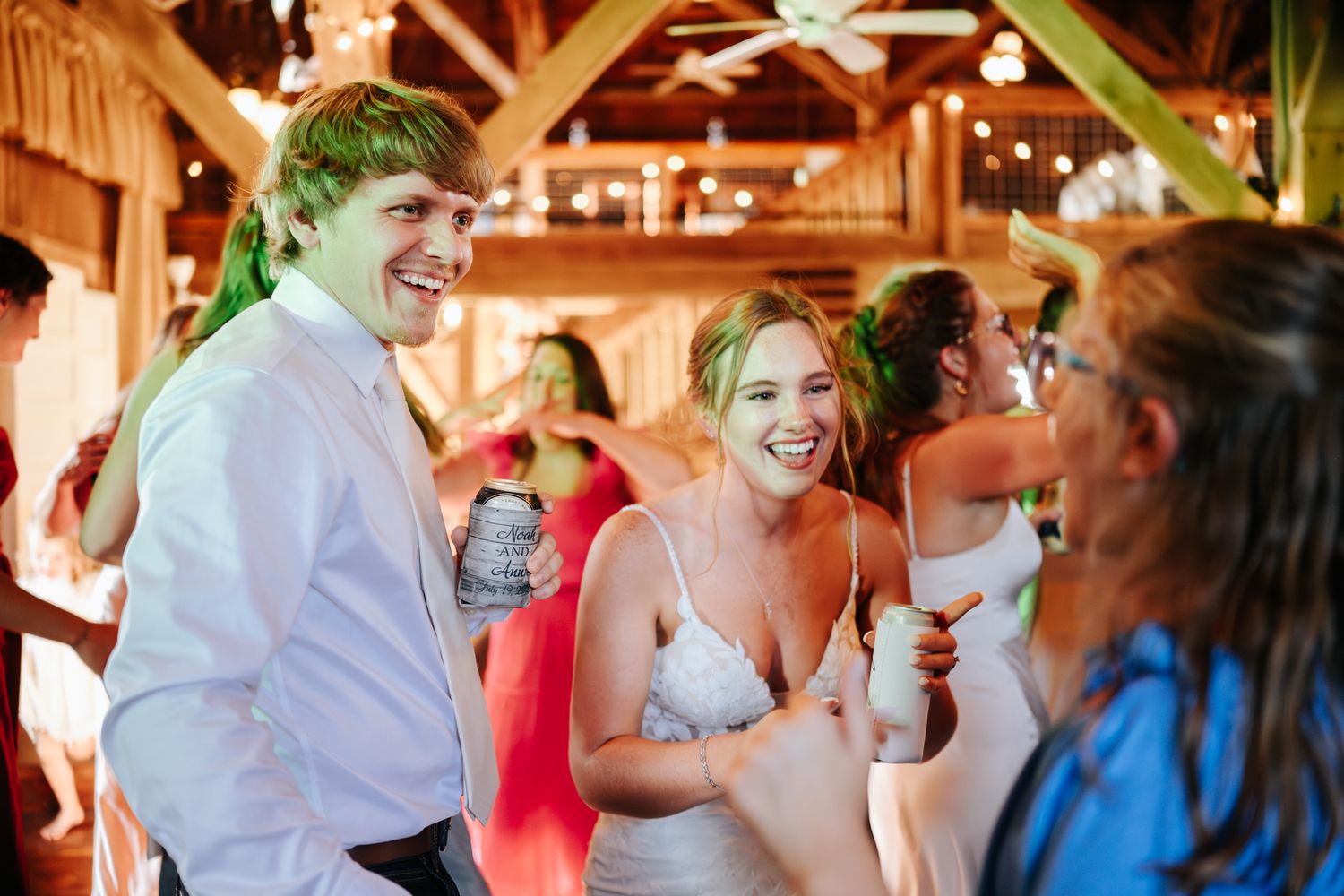 Wedding guests dance and celebrate in a warmly lit rustic venue.