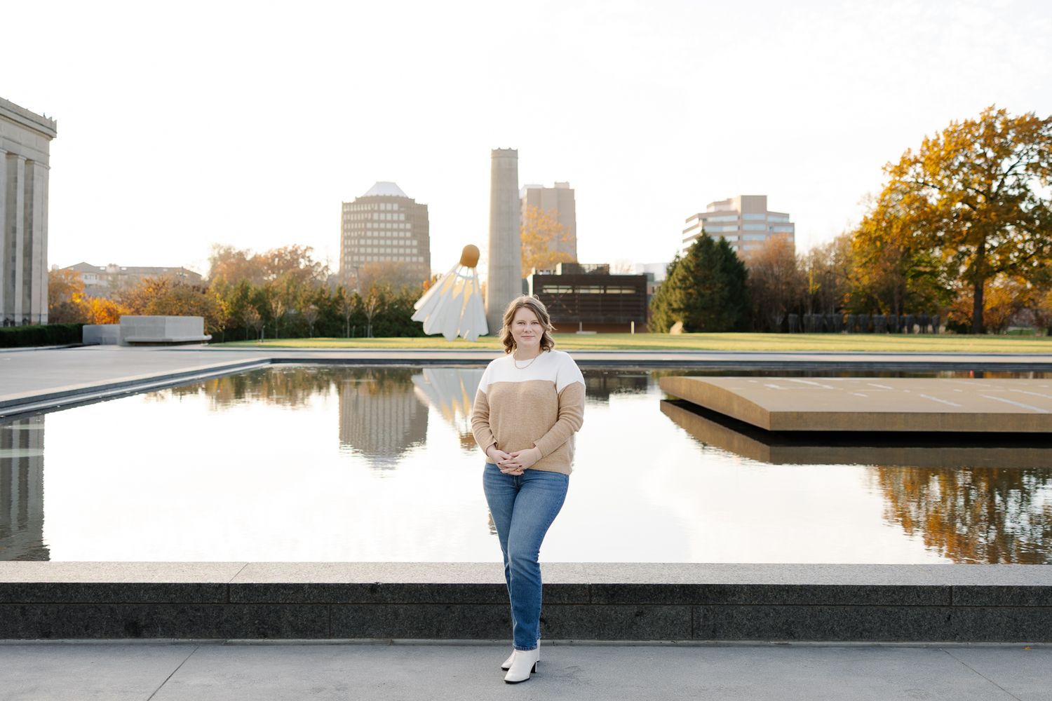 Urban landscape with reflecting pool and city buildings during golden hour.