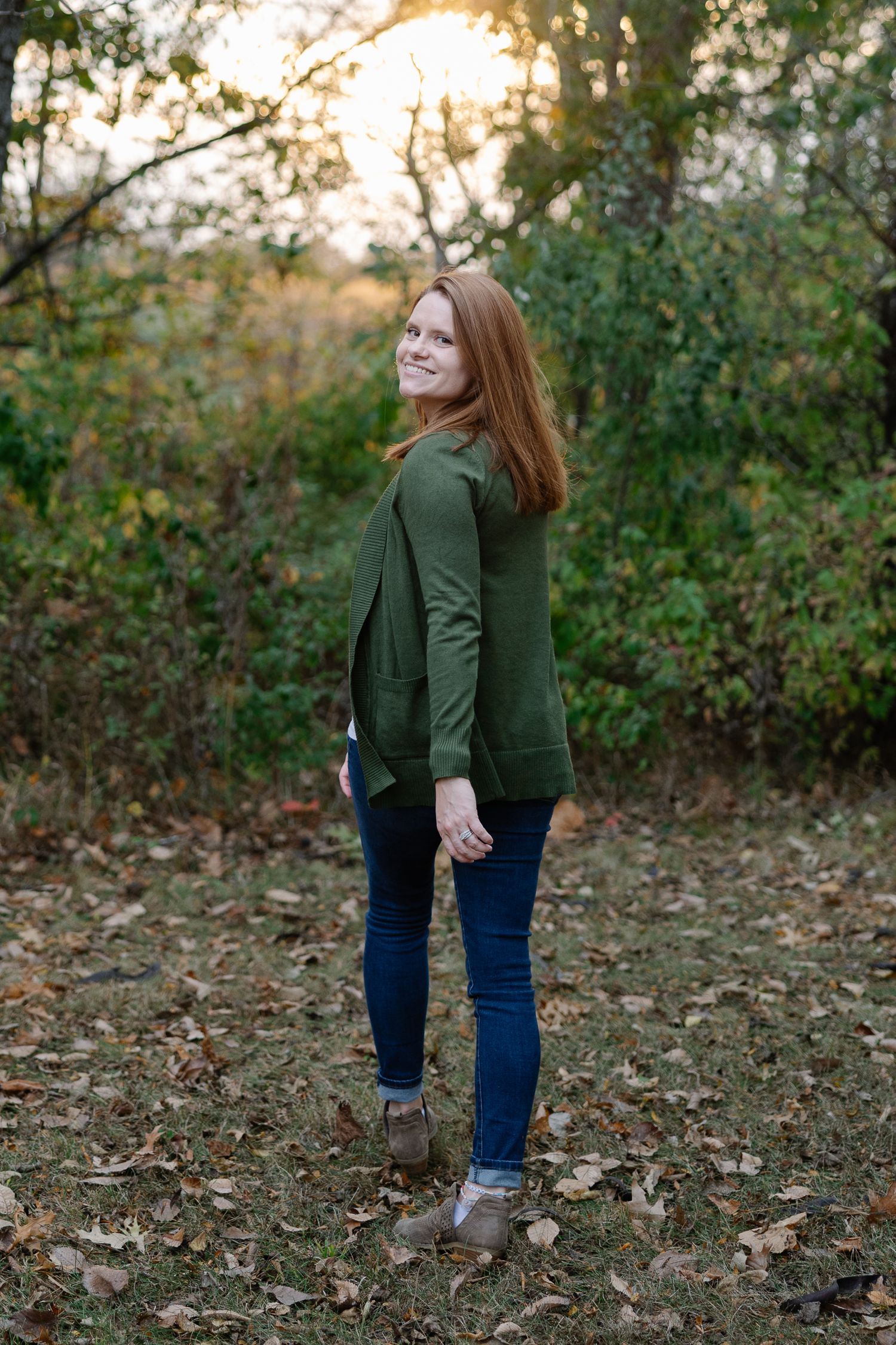 Full-length outdoor portrait in a forest setting during golden hour.