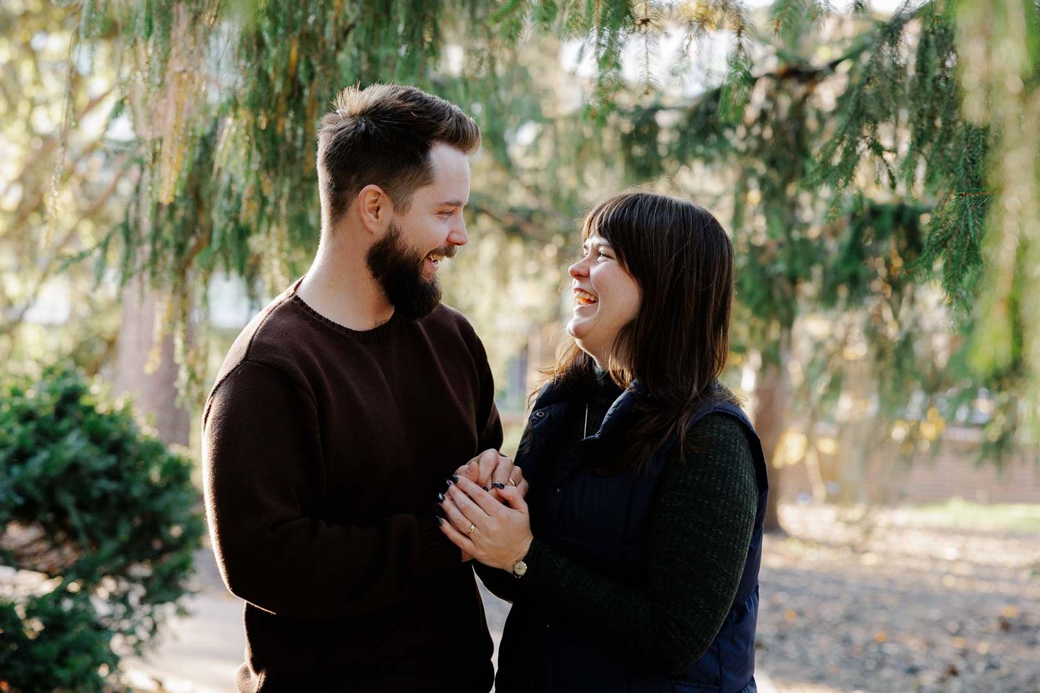 Romantic couple sharing tender moments under weeping willow trees in a park.