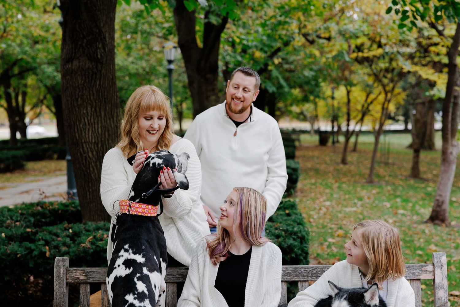 Family gathering outdoors with pets under fall trees.