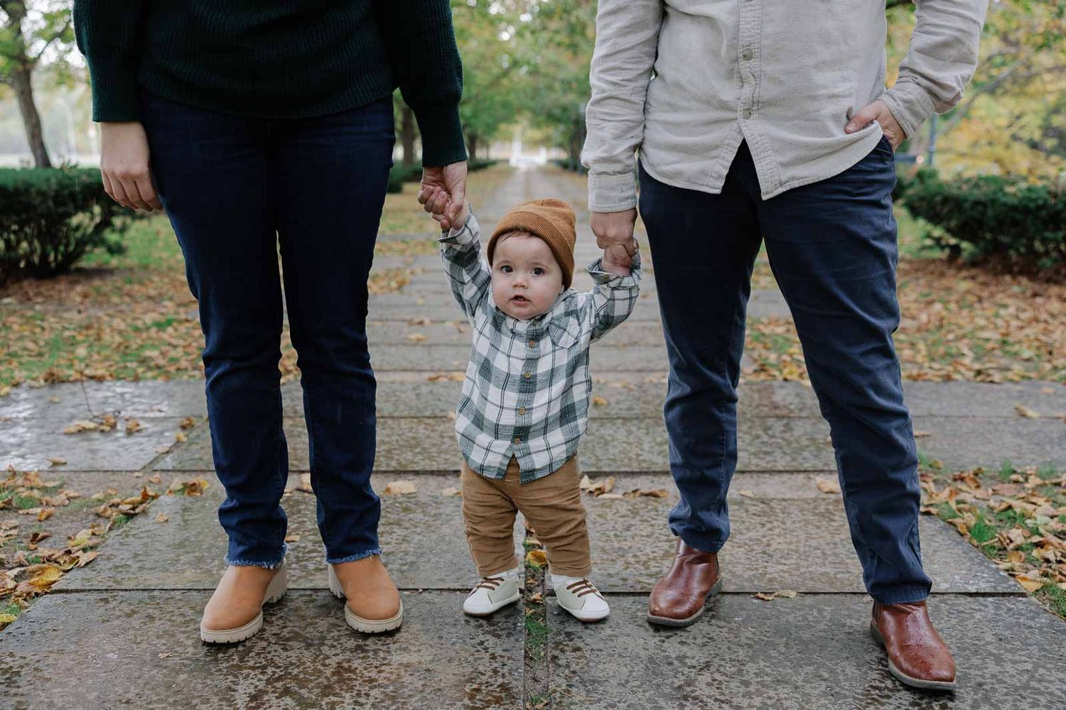 Family walking together on path during autumn with toddler learning to walk.