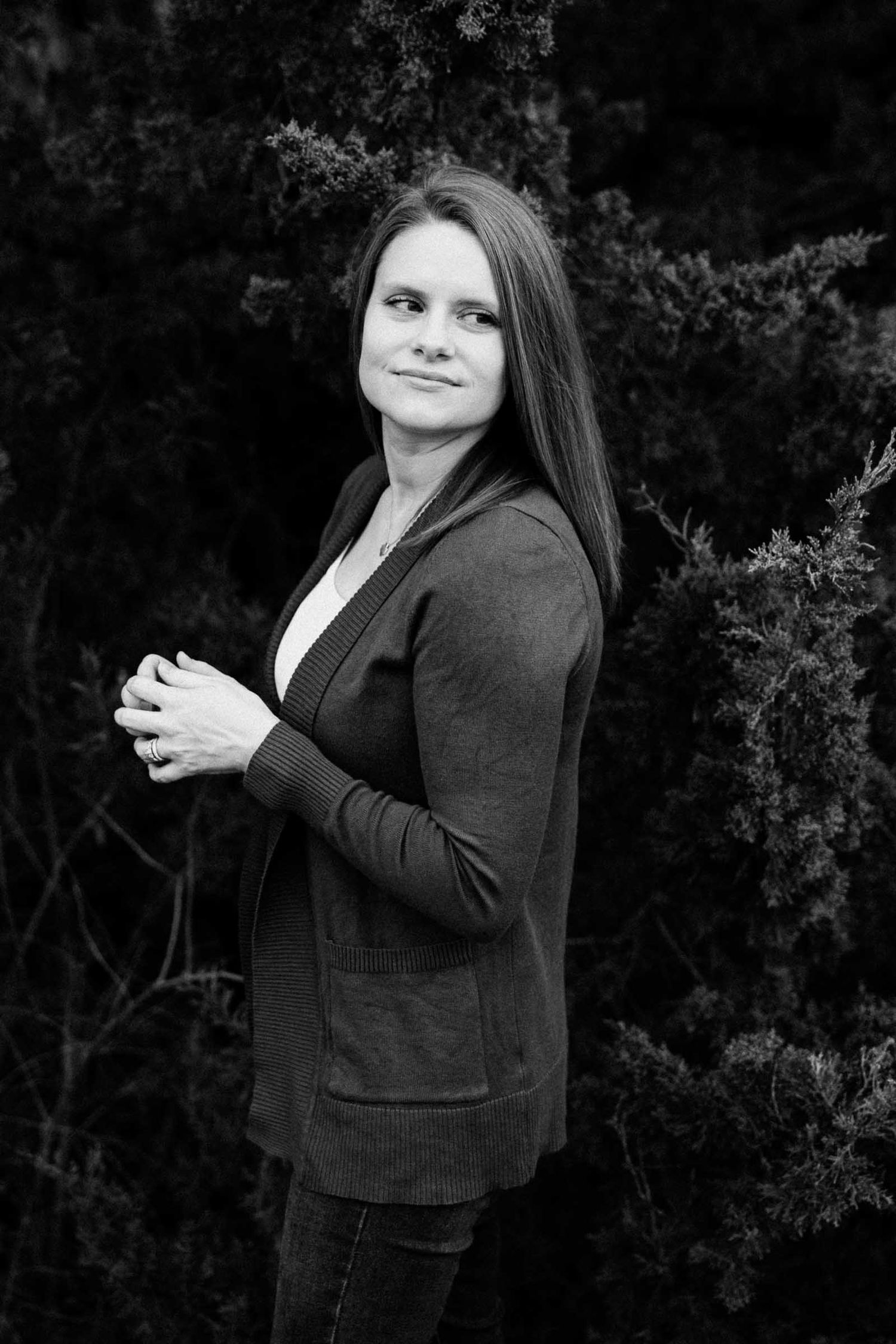 Black and white portrait against dark foliage background.