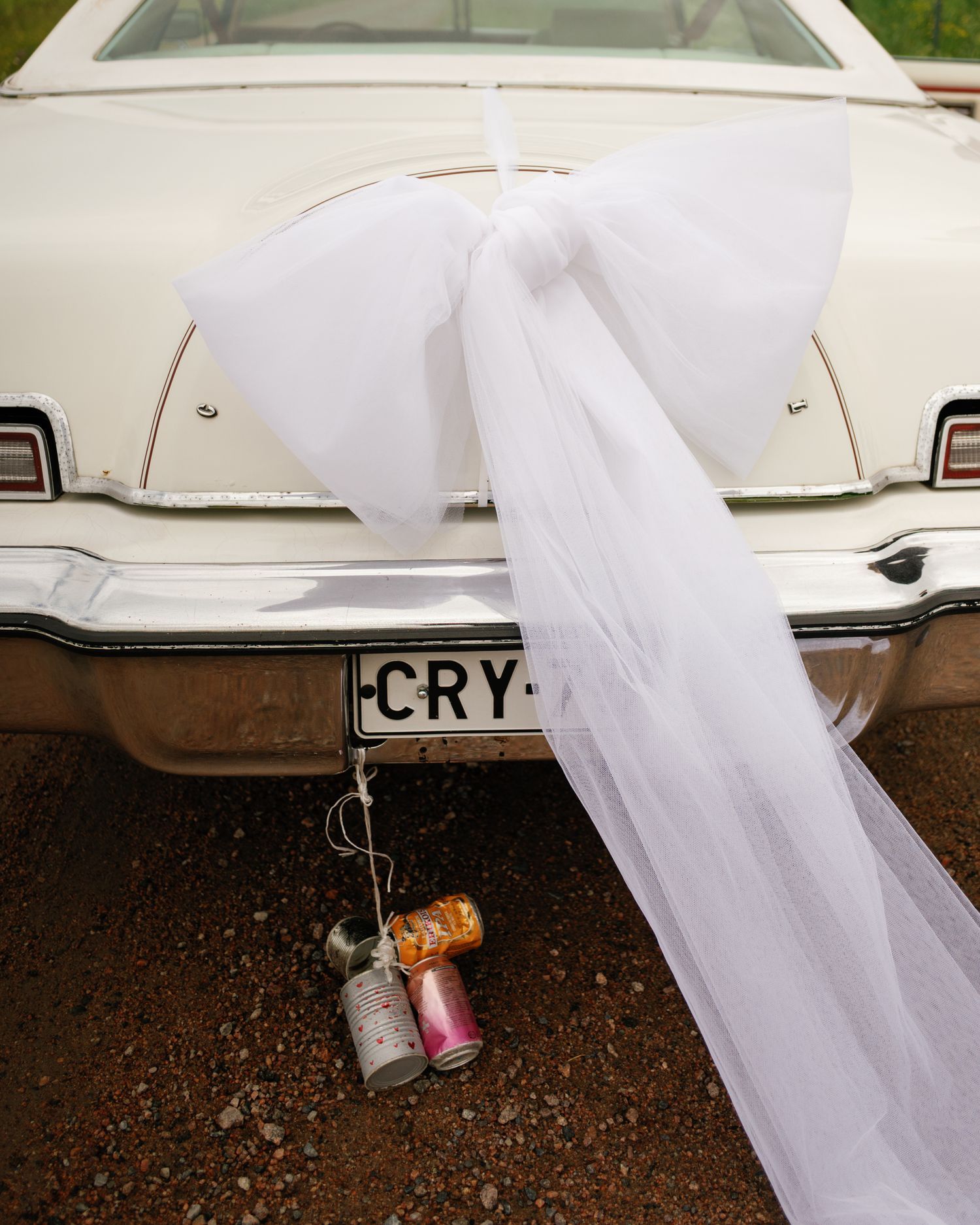 White wedding veil draped over a classic car with vintage details.