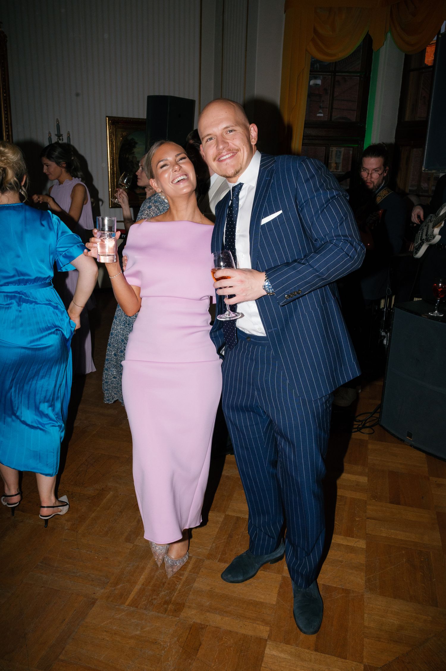 Couples dancing together at a social event on a wooden dance floor.
