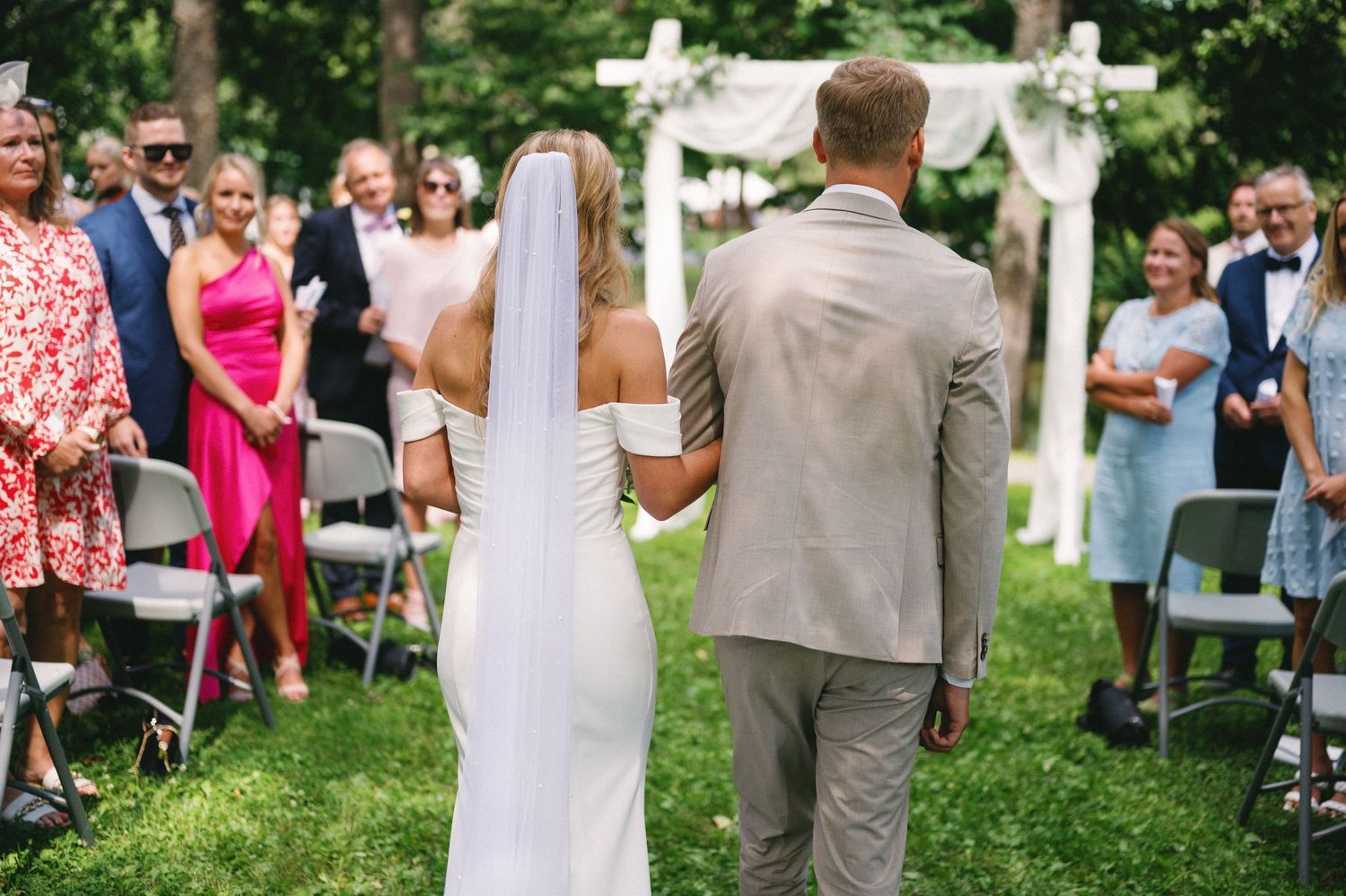 Wedding guests and decorations in a garden setting with white crosses visible.