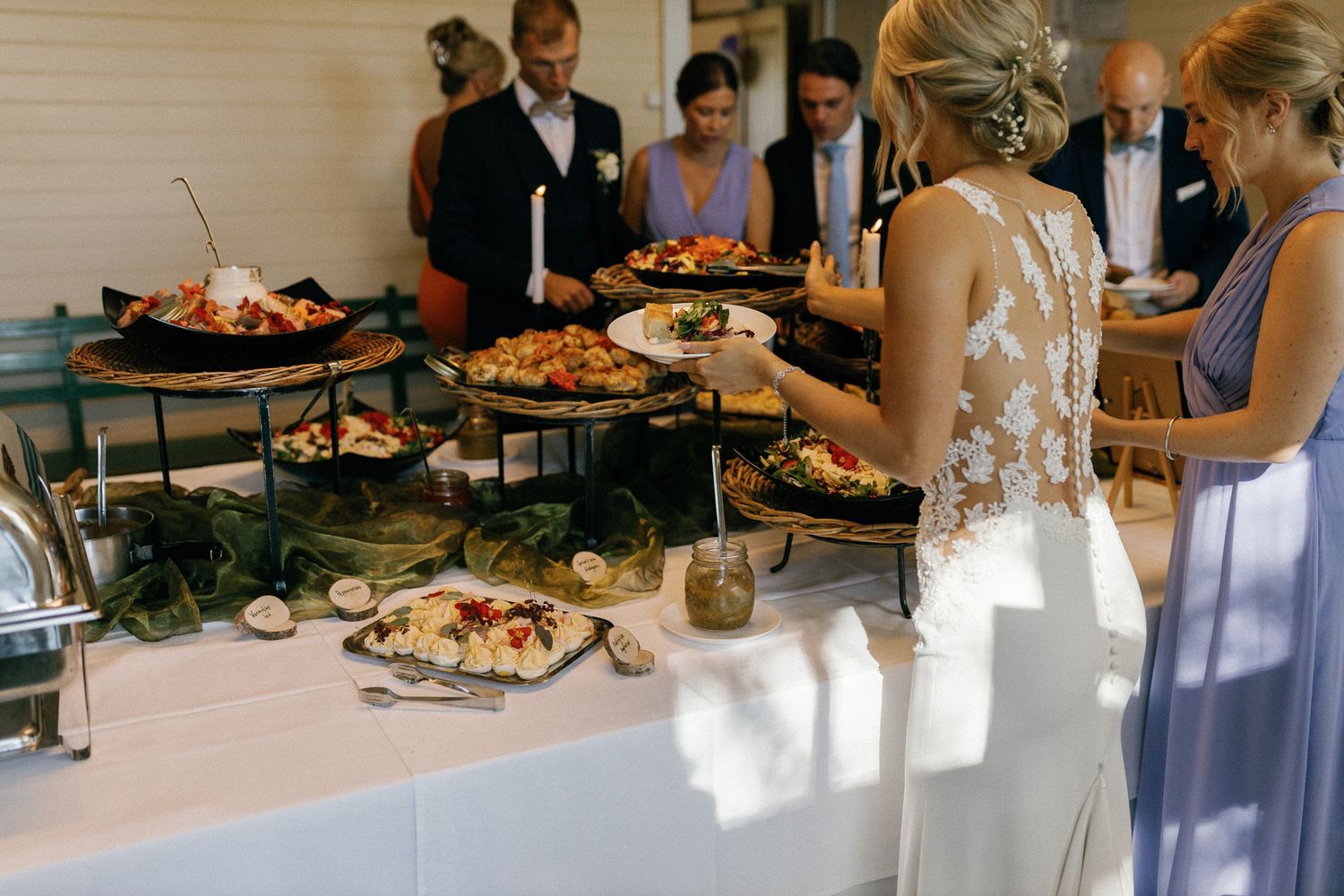 Wedding reception buffet setup with guests serving themselves food.