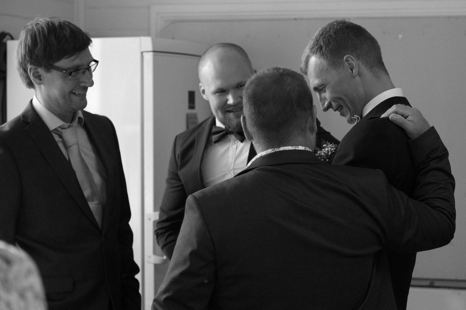 A group of men in suits having an informal conversation in black and white.