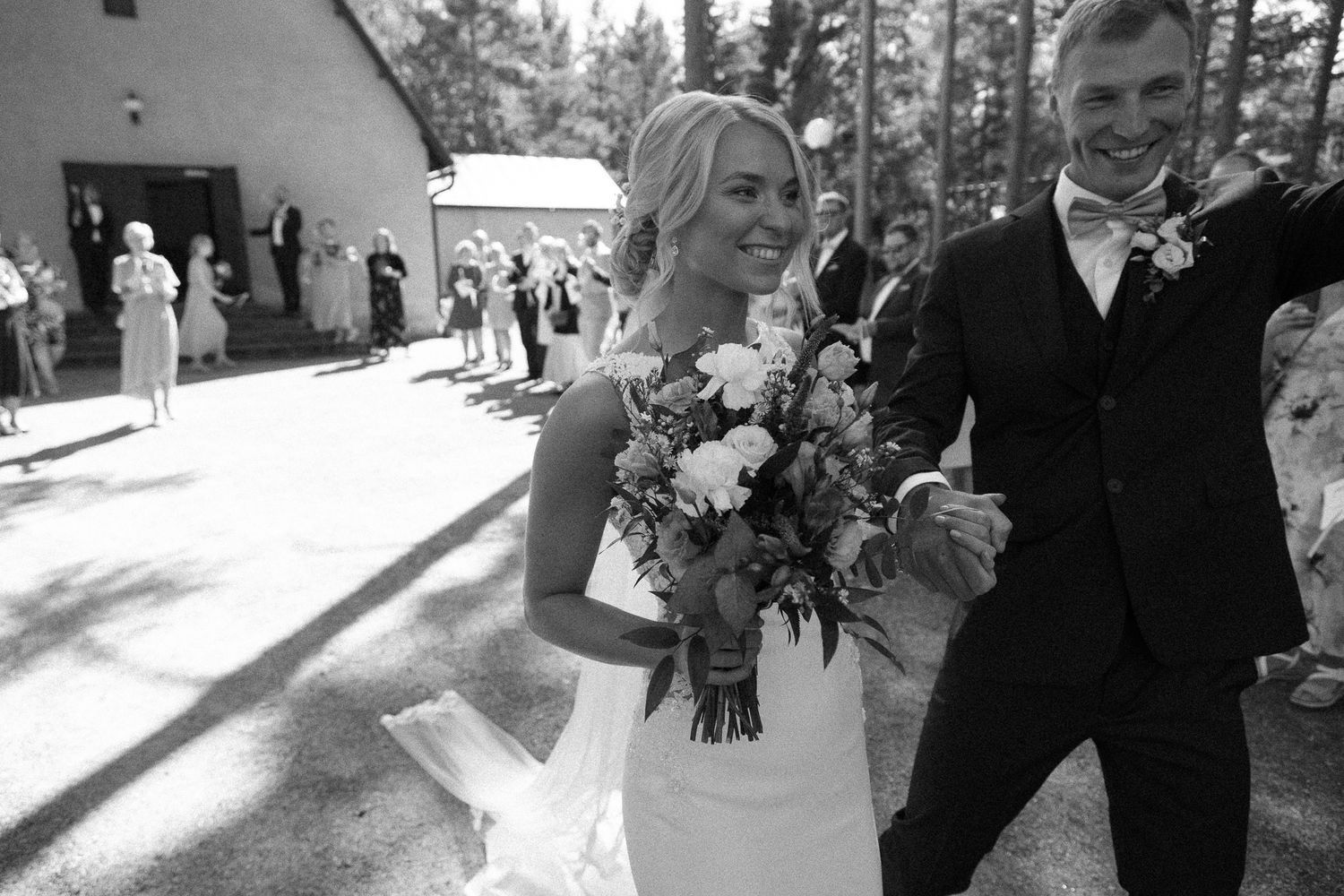 Couple exits chapel while wedding guests line the walkway in celebration.