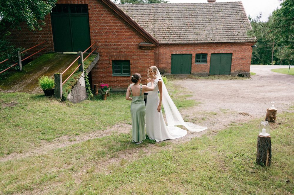 Wedding ceremony setup outside brick farmhouse with green surroundings.