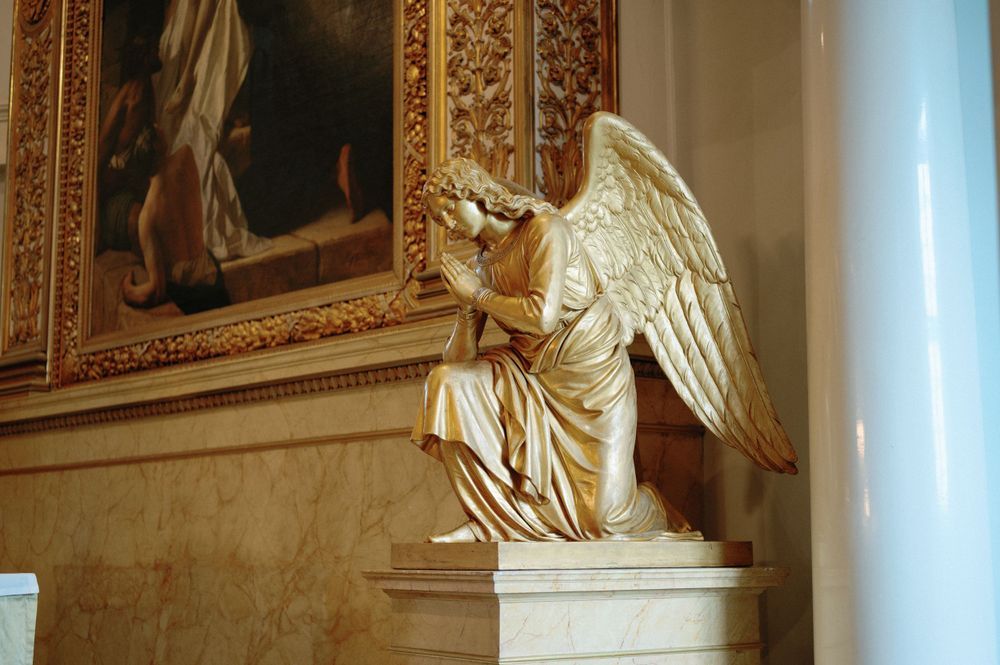 Ornate church interior featuring golden angel sculptures and decorative frames on walls.