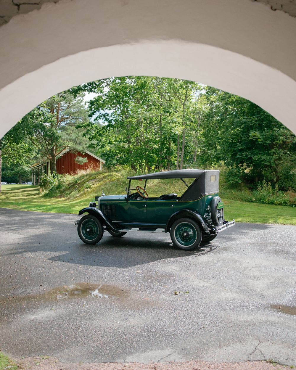 Panoramic view of vintage automobile under white arched portico.