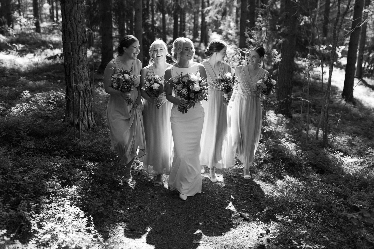 Black and white photo of bridesmaids lined up in a forest setting.