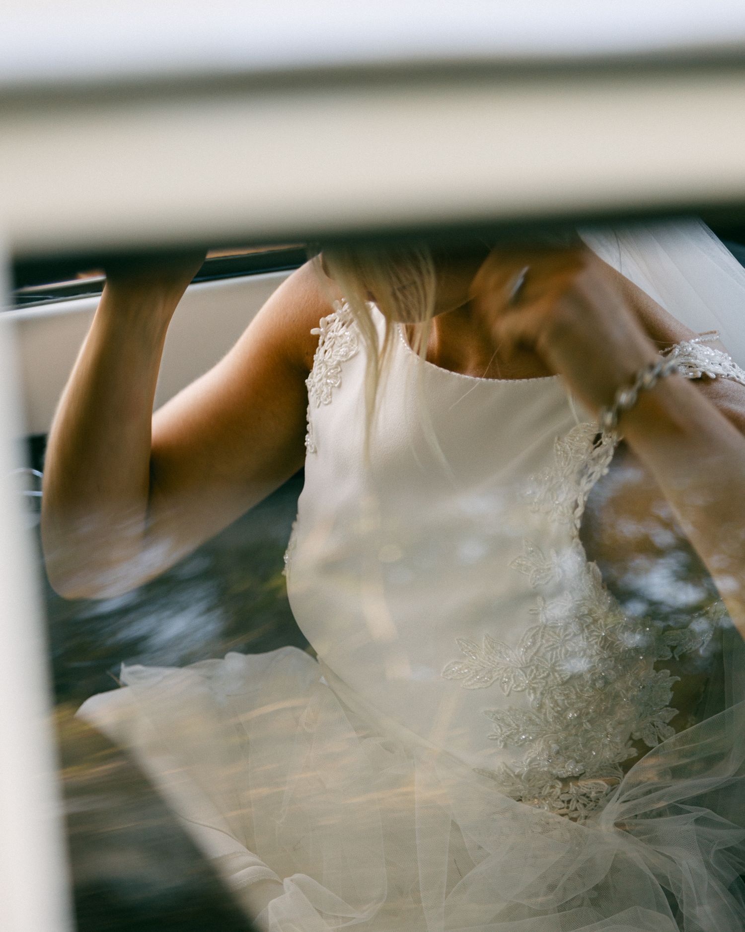 White wedding dress fabric detail shown through car window reflection.
