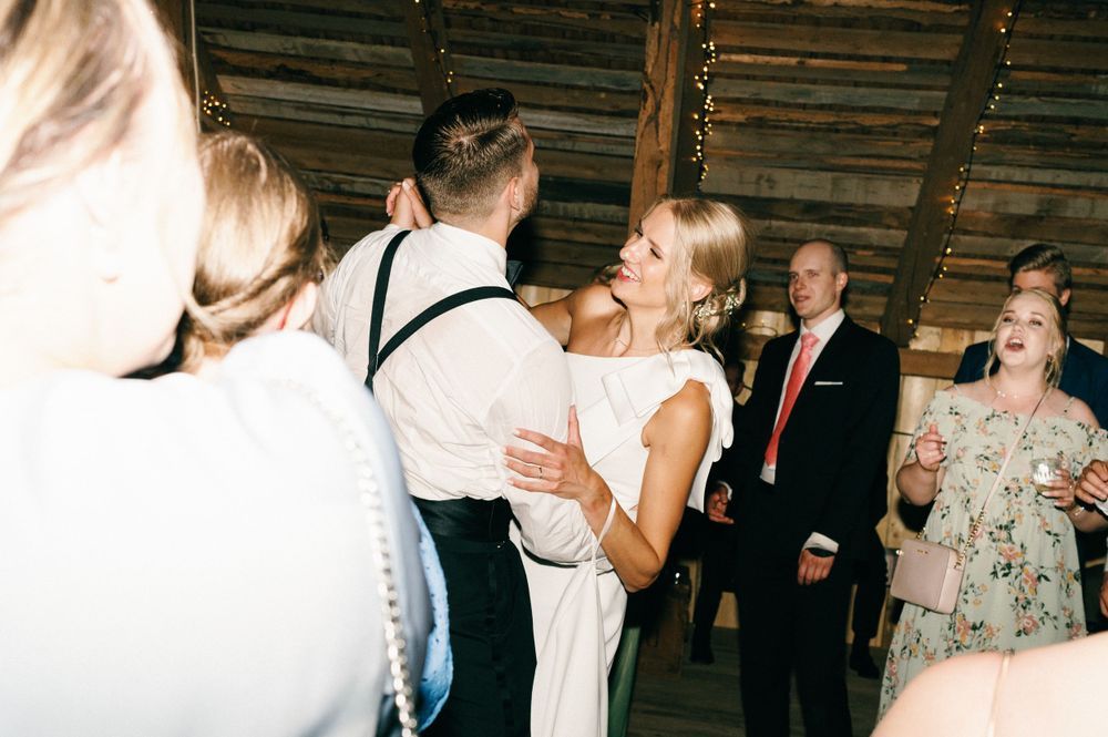 Wedding reception guests dancing and celebrating in a rustic indoor venue.