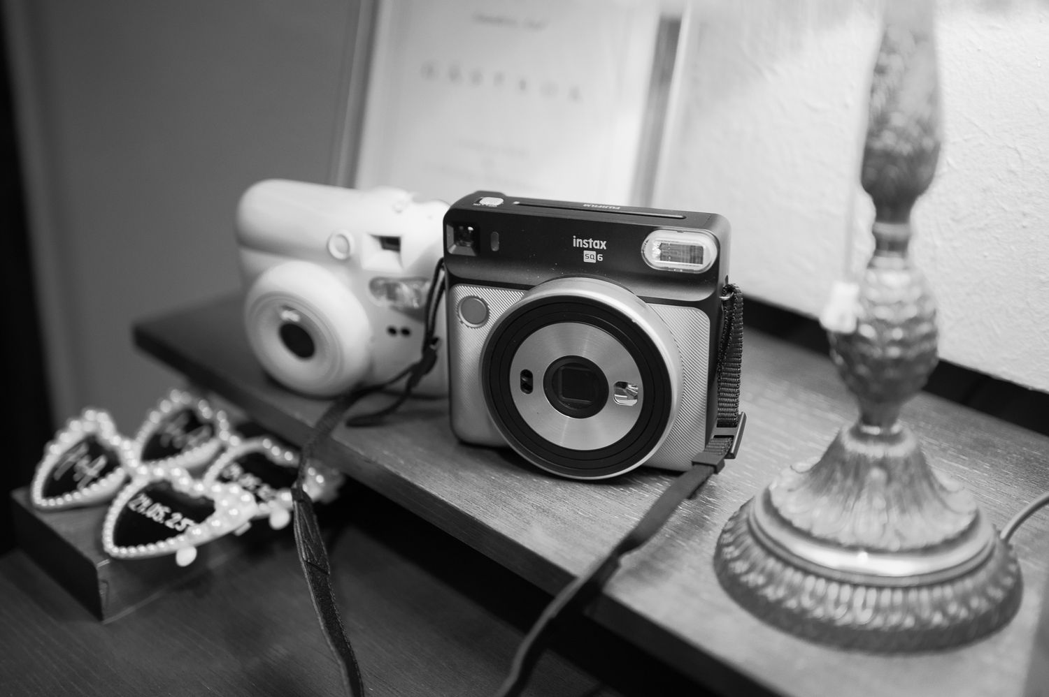 A series of black and white photographs showing vintage cameras, earbuds, and household items arranged in a filmstrip style layout.