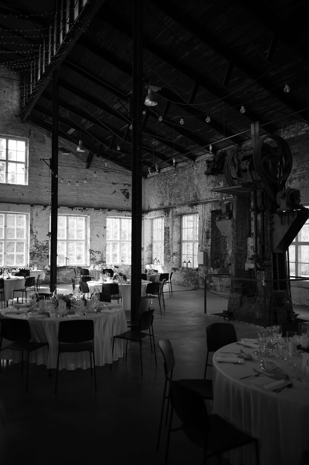 Dramatic black and white view of an industrial event space with exposed ceiling beams.