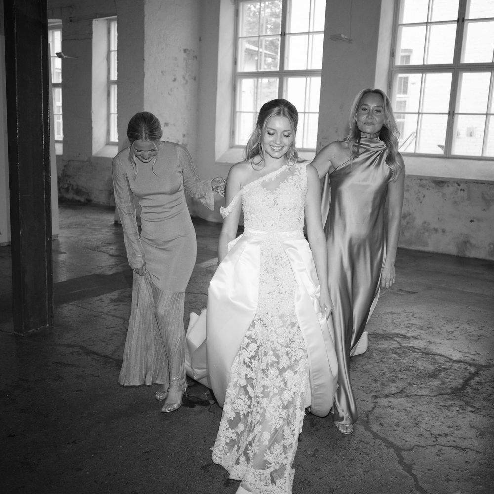 Black and white photo of a group in formal attire in an industrial-style venue.
