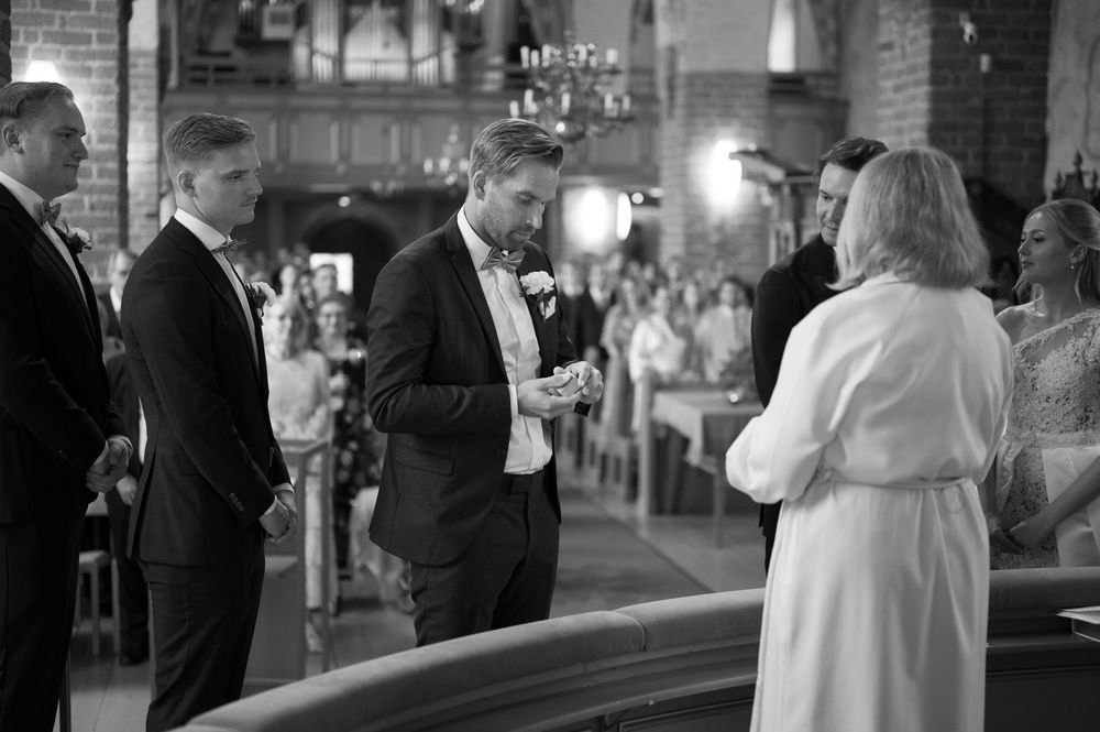 A black and white photo captures an intimate moment during a church wedding ceremony.