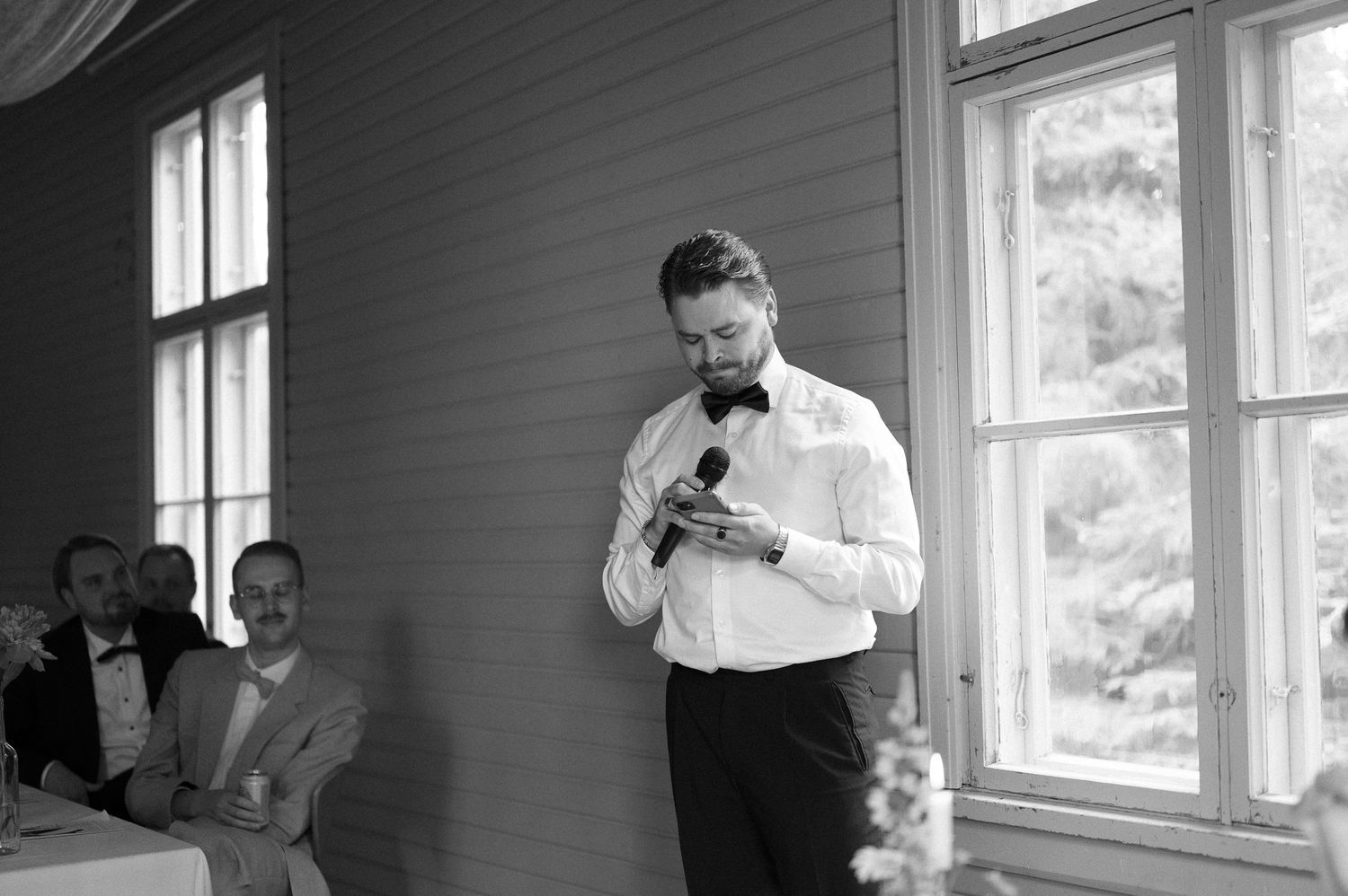 A speaker in formal attire addresses guests during an indoor event.