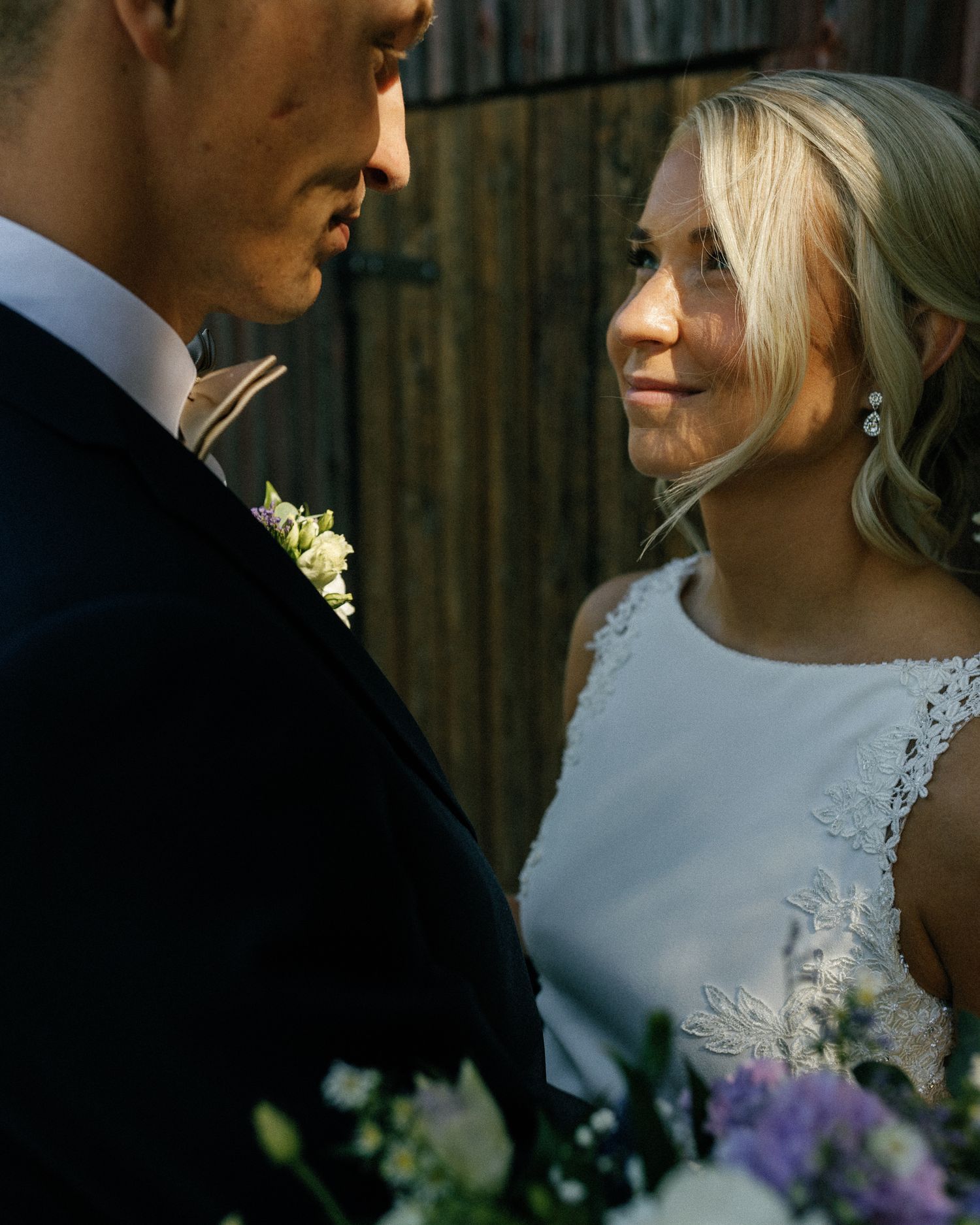 Intimate wedding portraits showing tender moments between newlyweds near wooden walls.