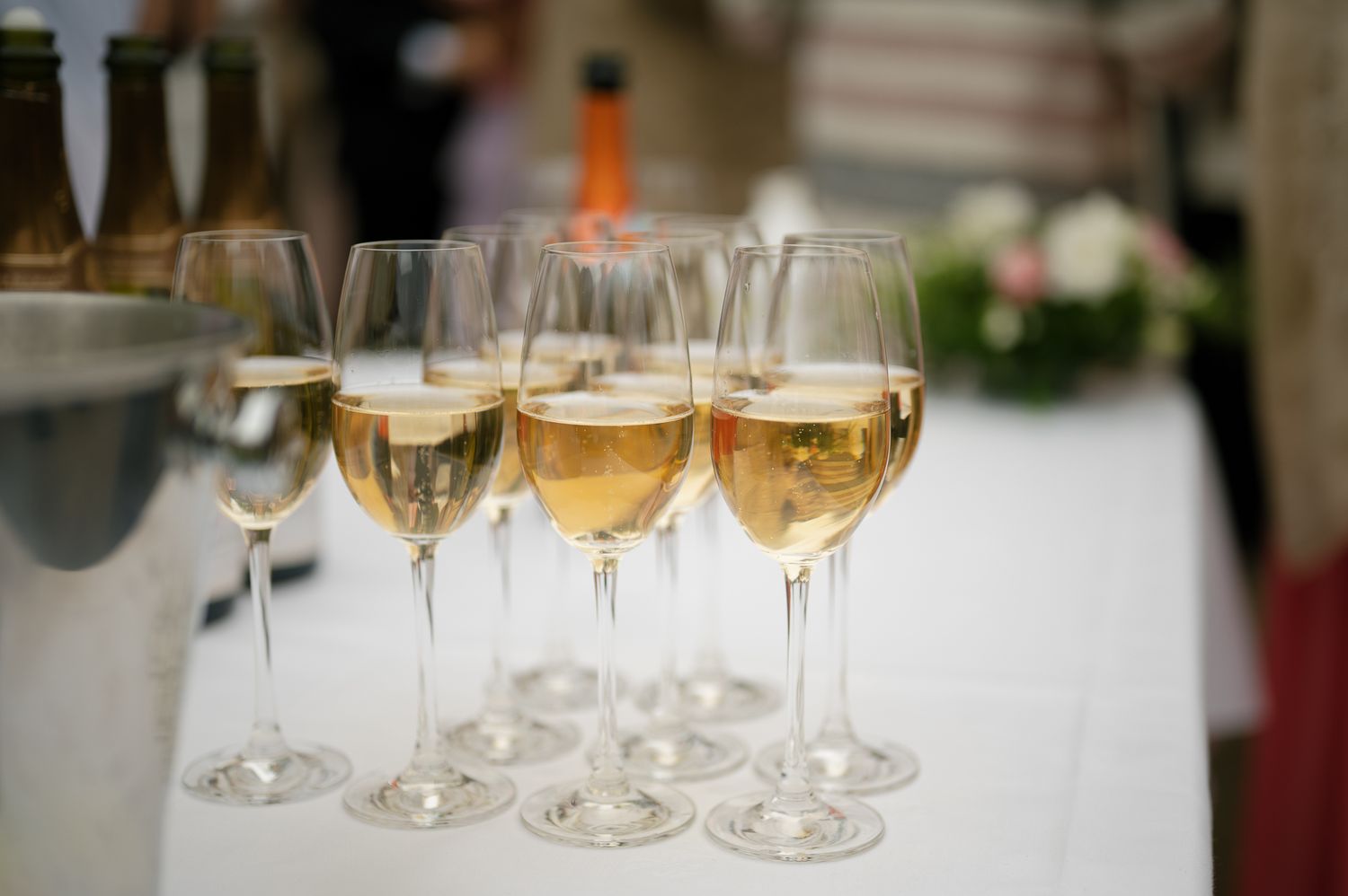 Several champagne flutes filled with golden sparkling wine sit elegantly on a white tablecloth at an event.