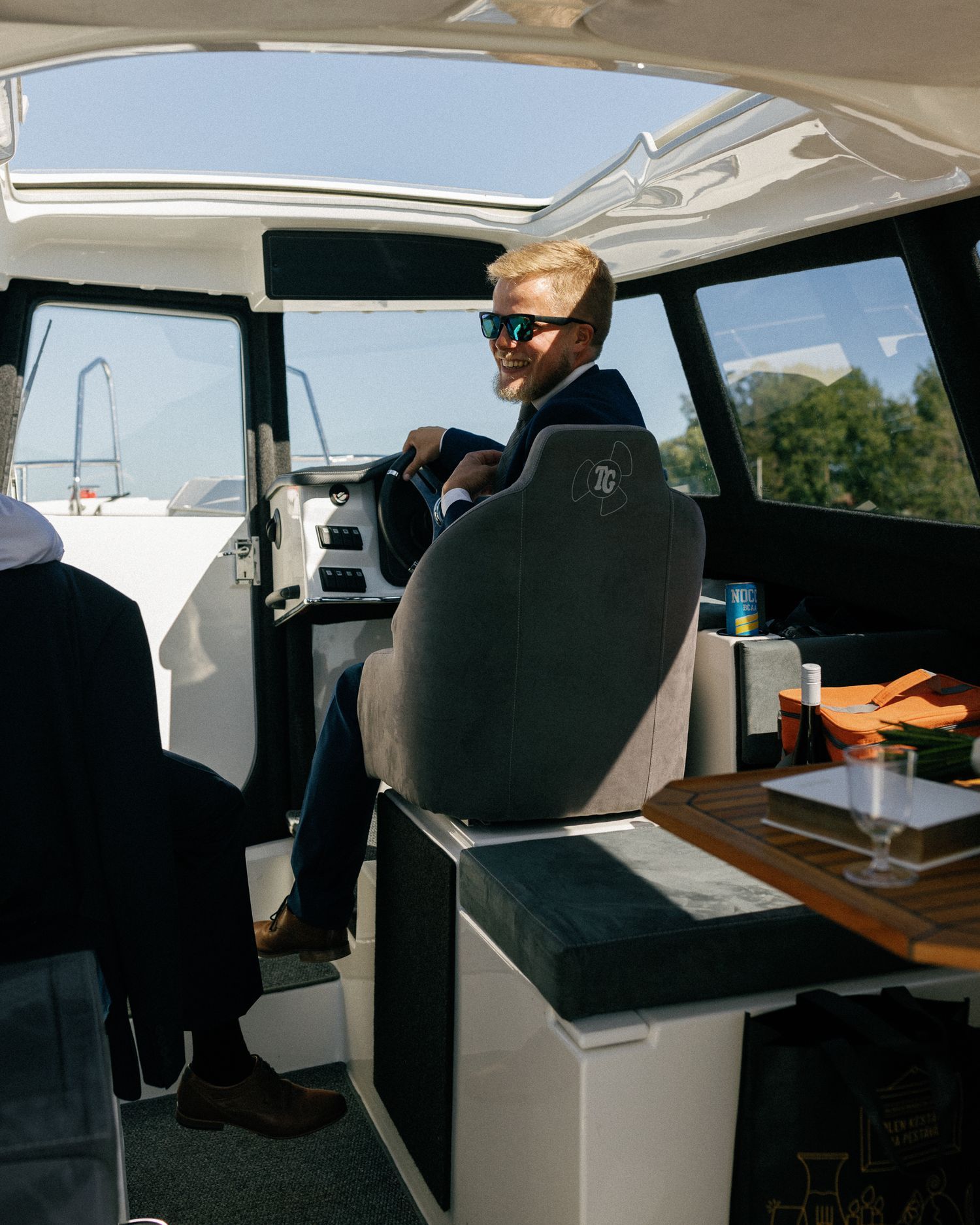 Interior view of boat cabin with captain at helm and navigation equipment.