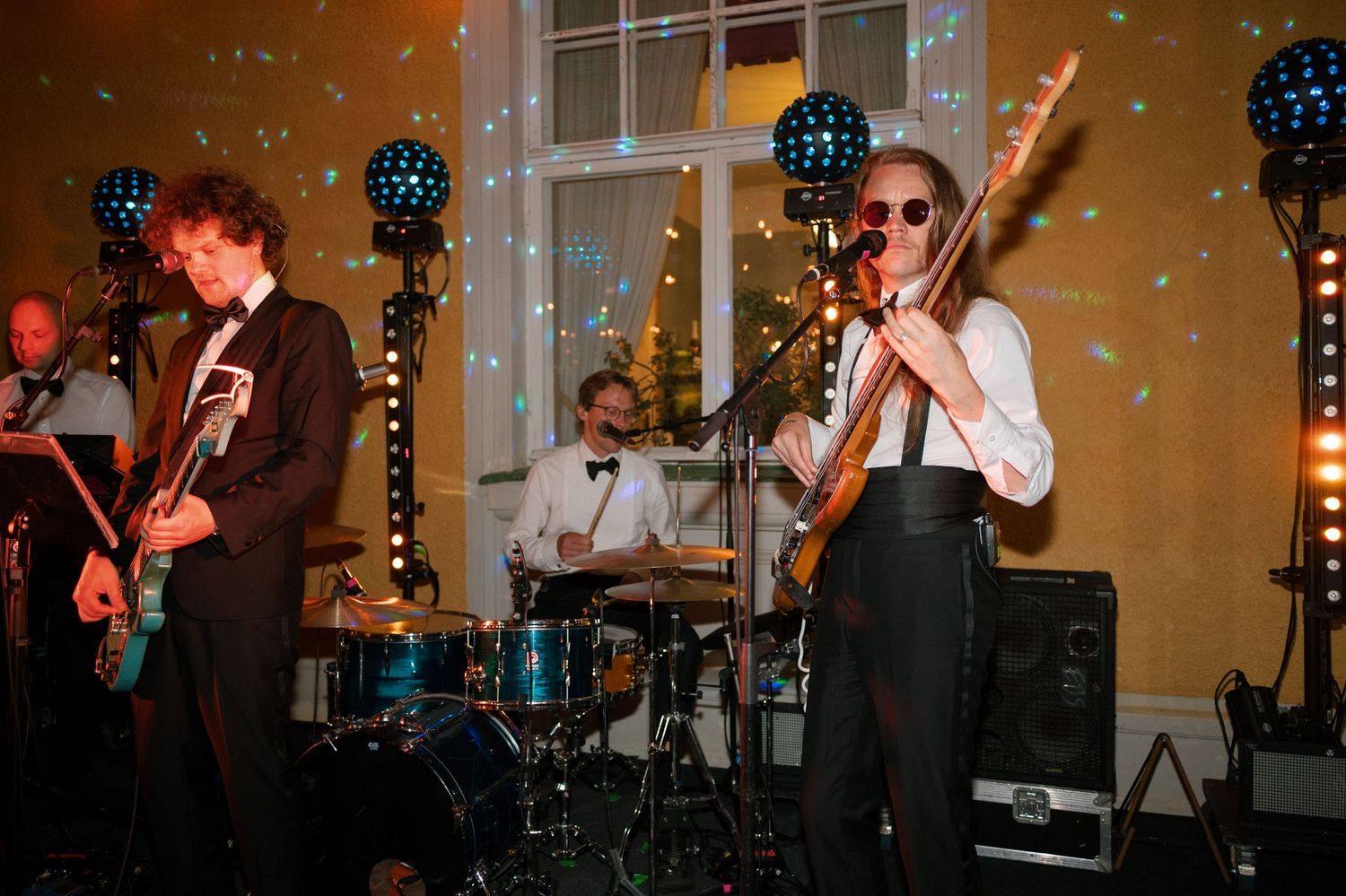 Wedding band performs on stage with instruments and lighting setup.